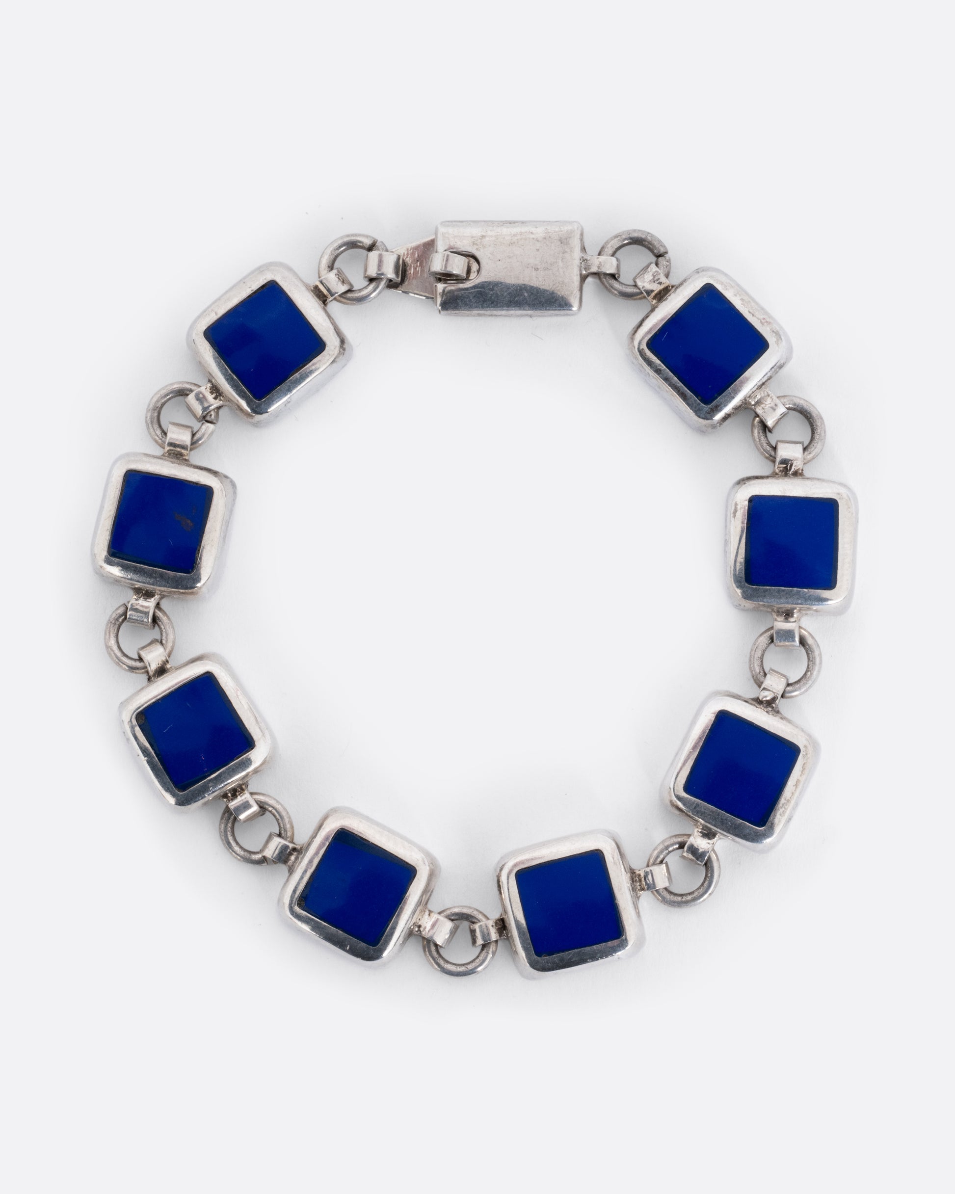 A silver bracelet with lapis squares joined by thick circular links, shown from the front.