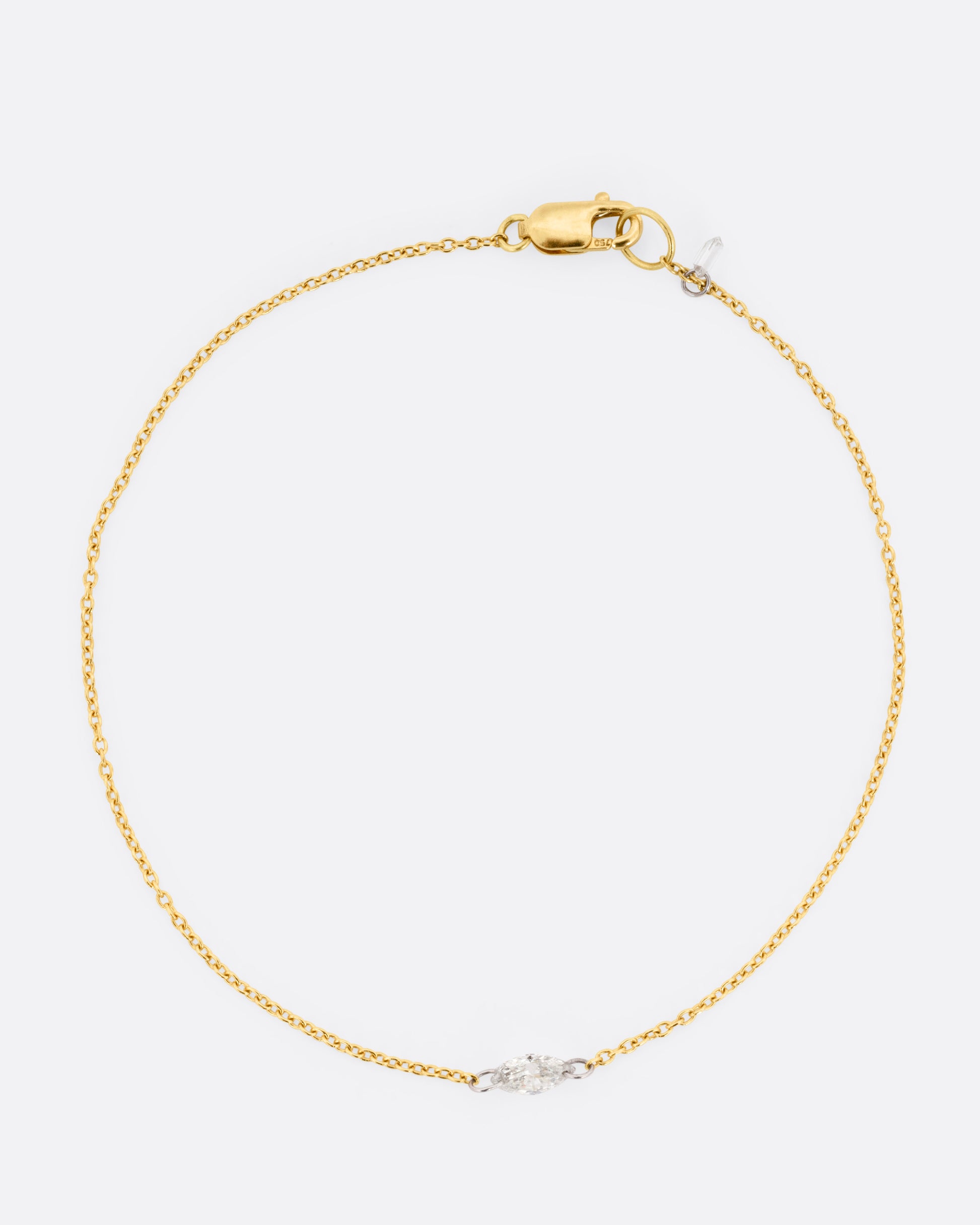 A  yellow gold cable chain bracelet with platinum jump rings and a free set marquise diamond.  Shown from the front.