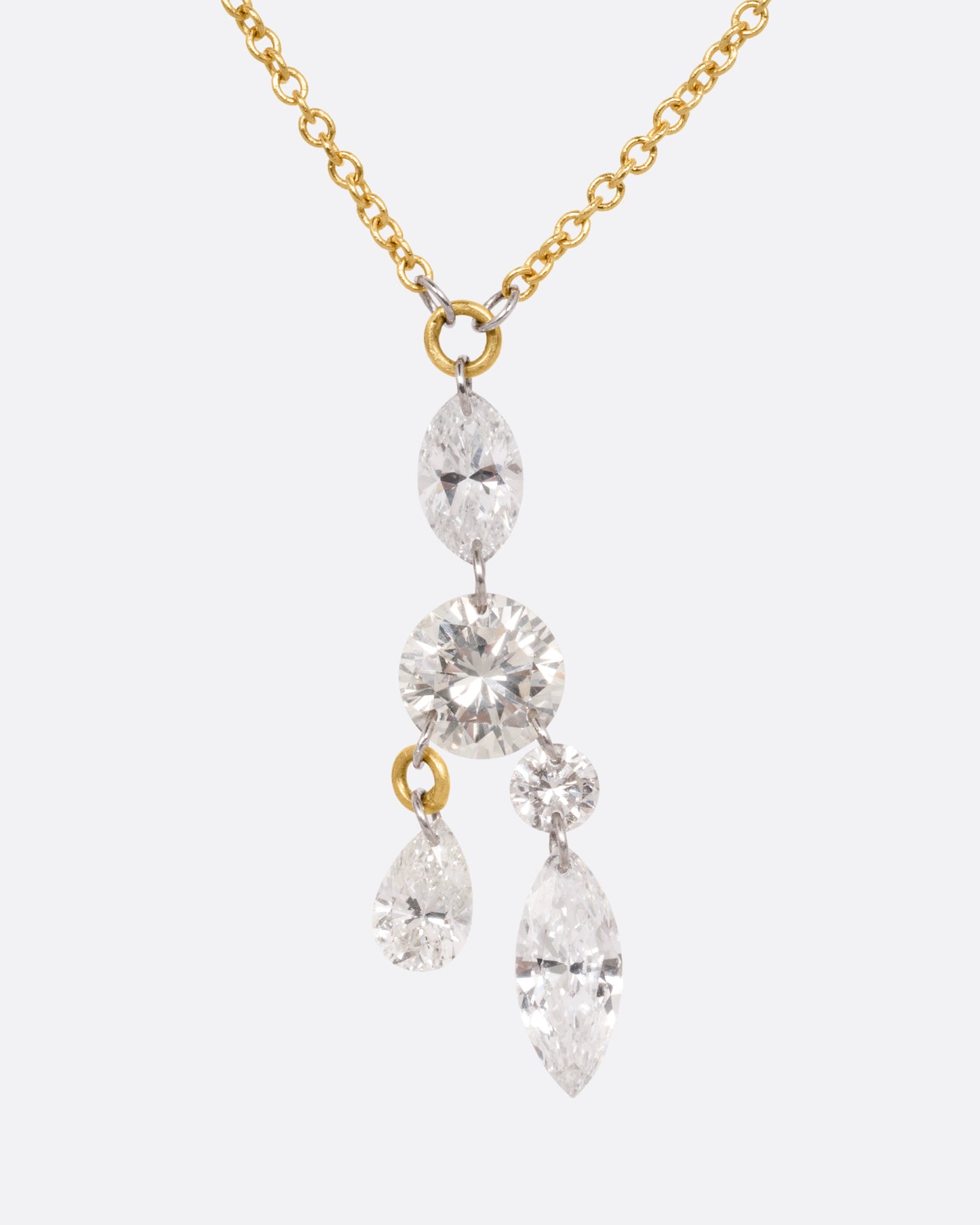 A yellow gold cable chain necklace with an arrangement of free set round, marquise, and pear shaped diamonds in platinum jump rings, shown from the front.