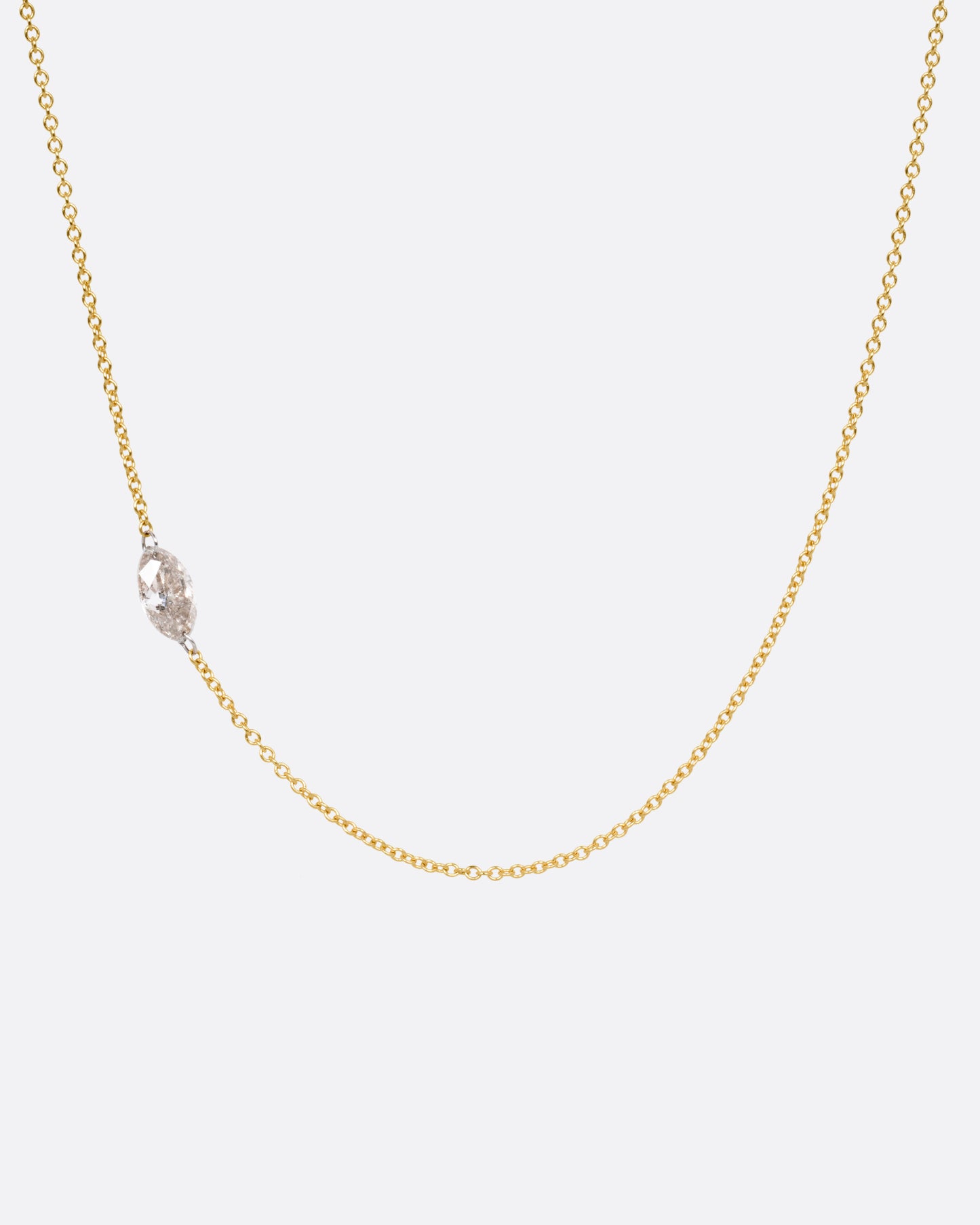 A yellow gold cable chain necklace with platinum jump rings and a free set marquise diamond, asymmetrically set. Shown from the front. 