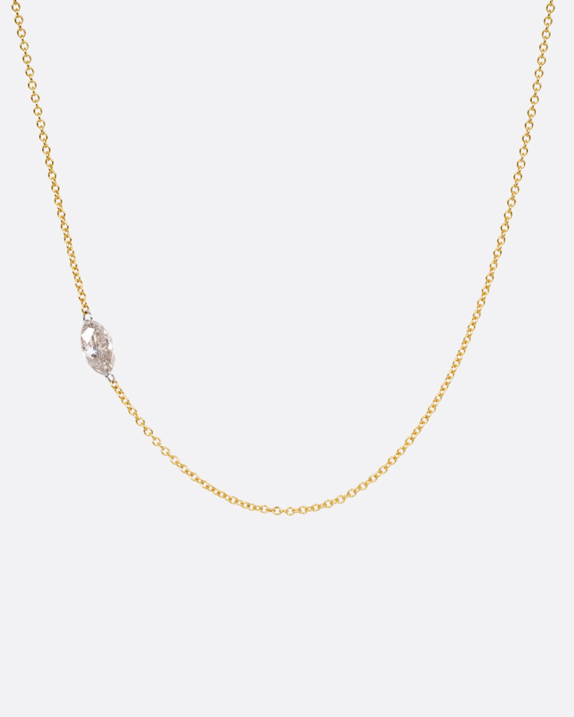A yellow gold cable chain necklace with platinum jump rings and a free set marquise diamond, asymmetrically set. Shown from the front. 