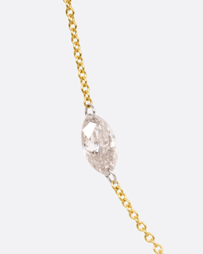 Yellow gold floating marquise diamond necklace, close view of the marquise diamond held by platinum rings