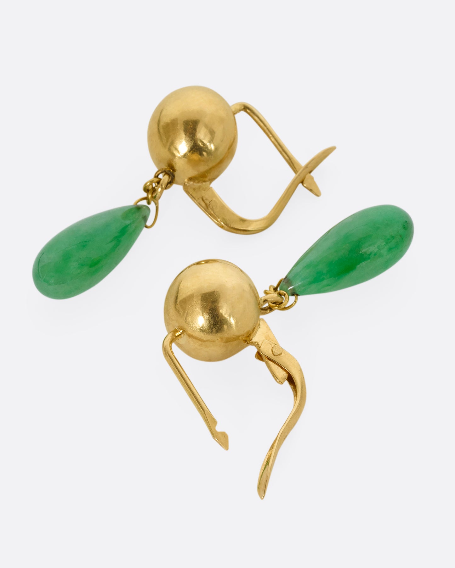 A pair of yellow gold ball earrings with teardrop jade drops. Shown laying flat.