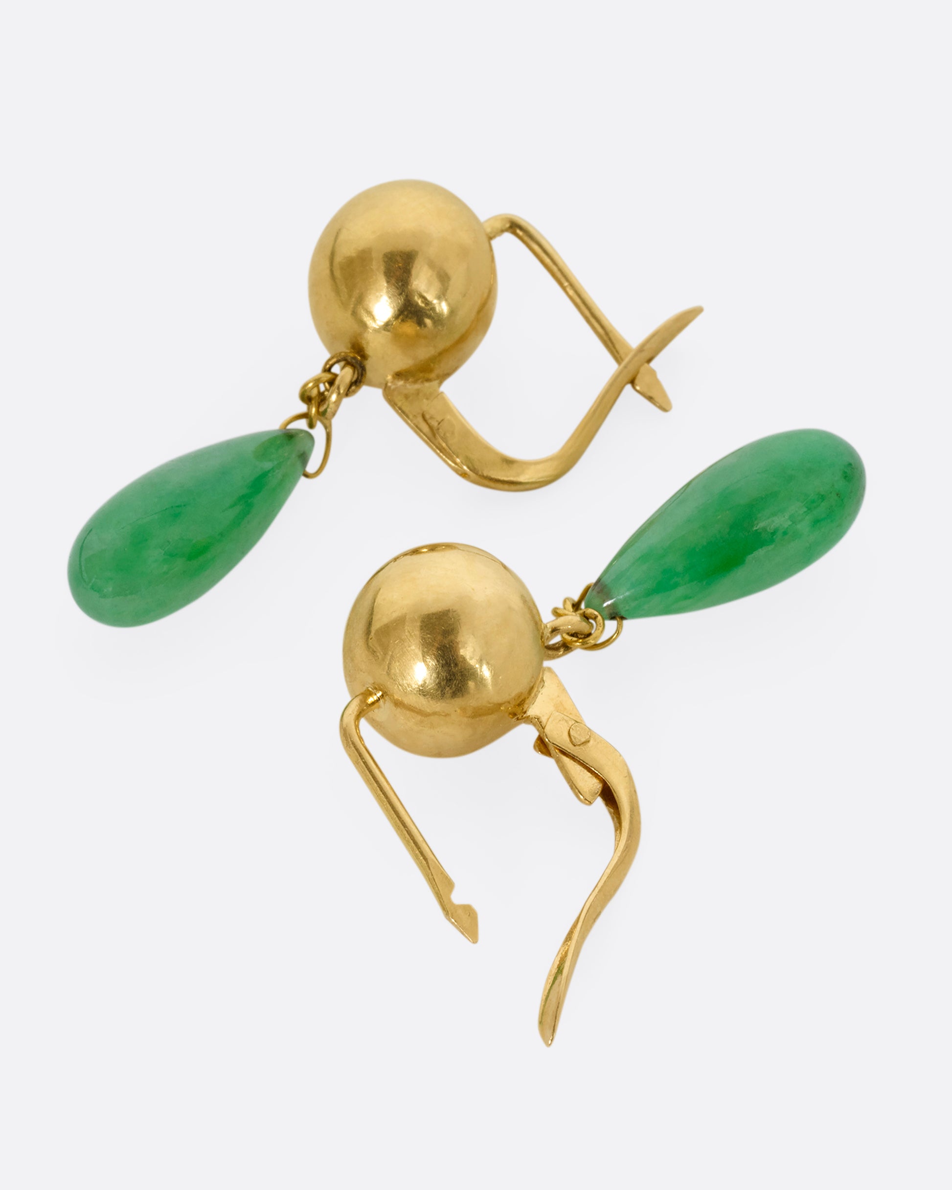 A pair of yellow gold ball earrings with teardrop jade drops. Shown laying flat.