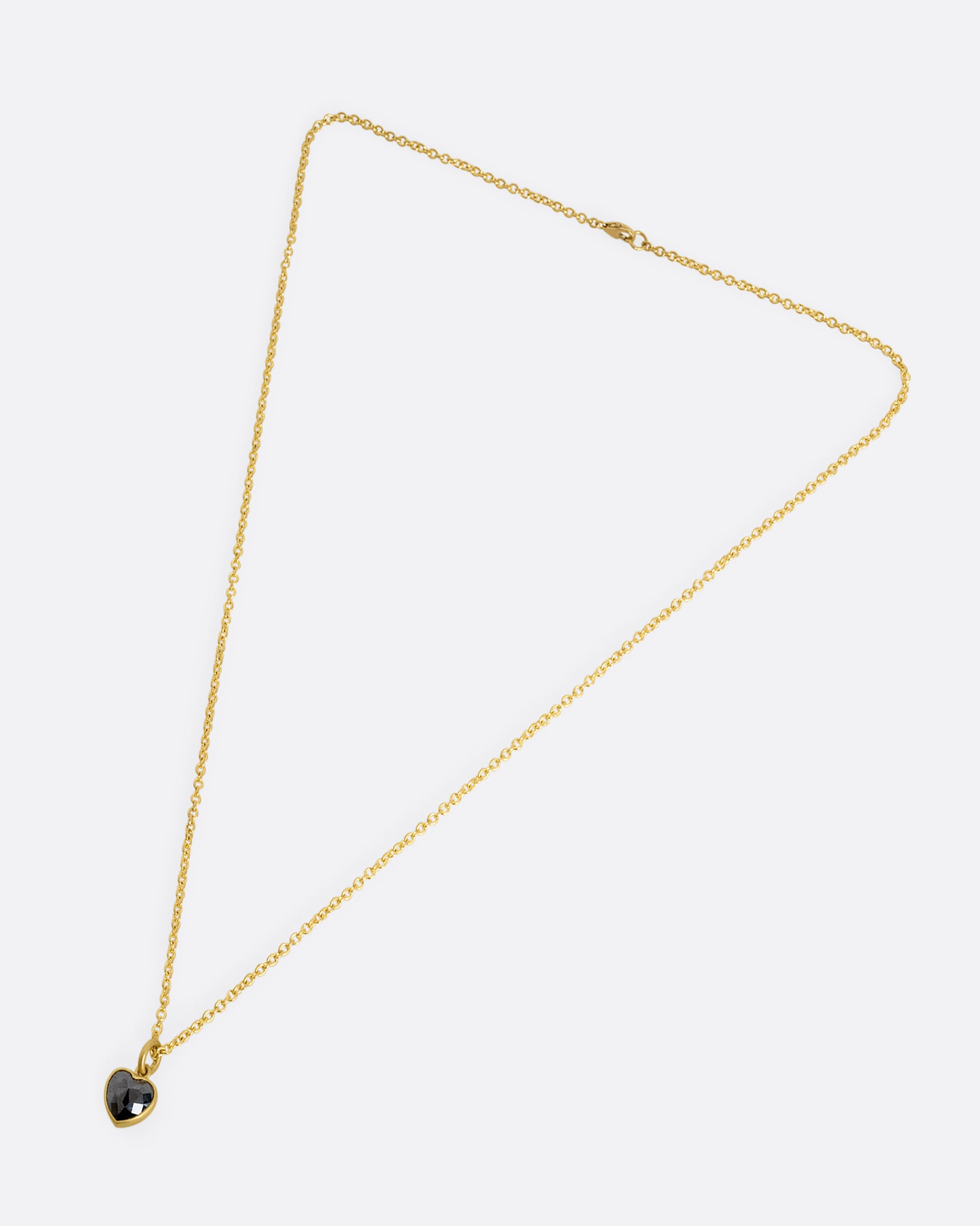 yellow gold necklace with heart shaped black diamond shown from afar