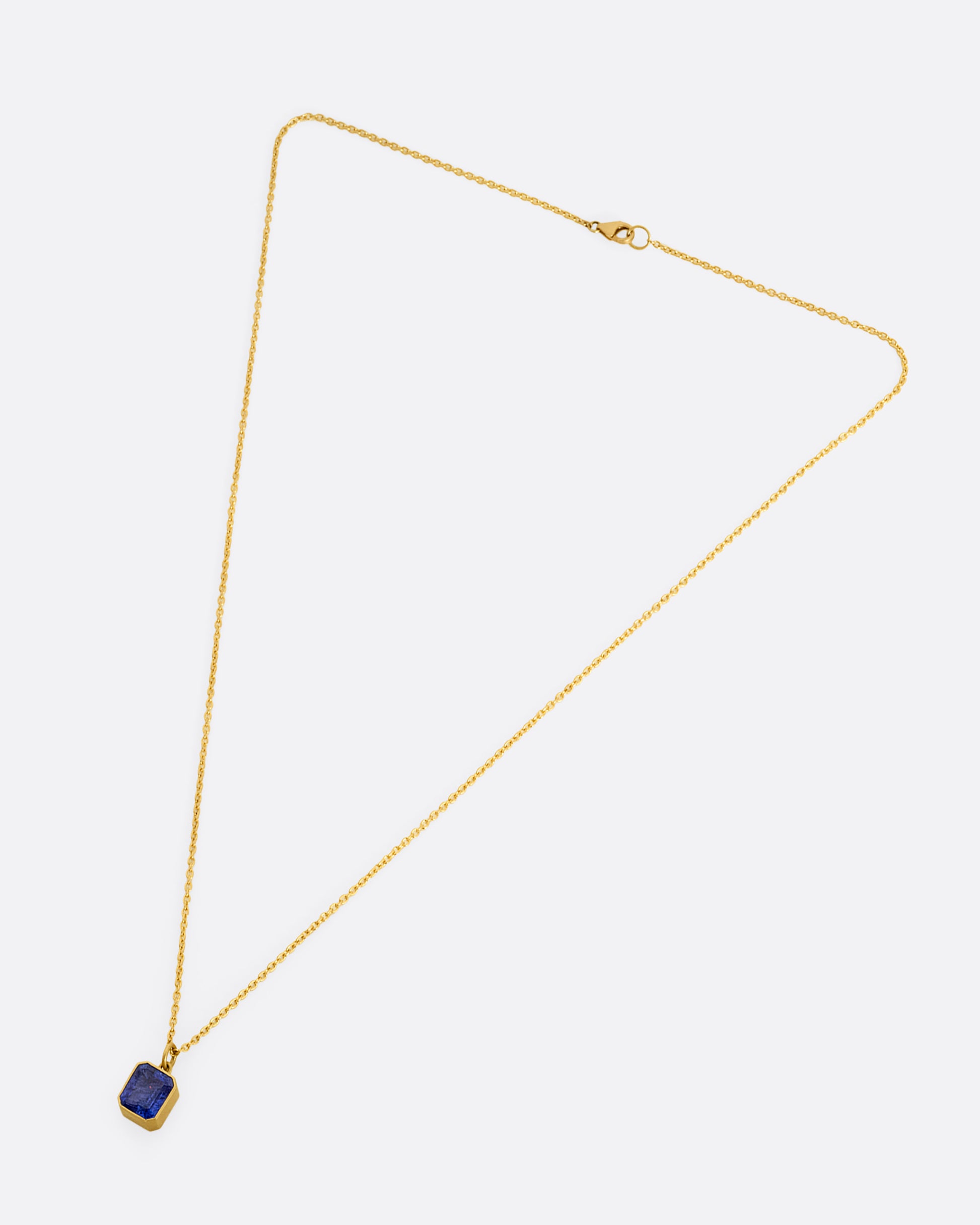 yellow gold necklace with an emerald cut tanzanite shown from afar