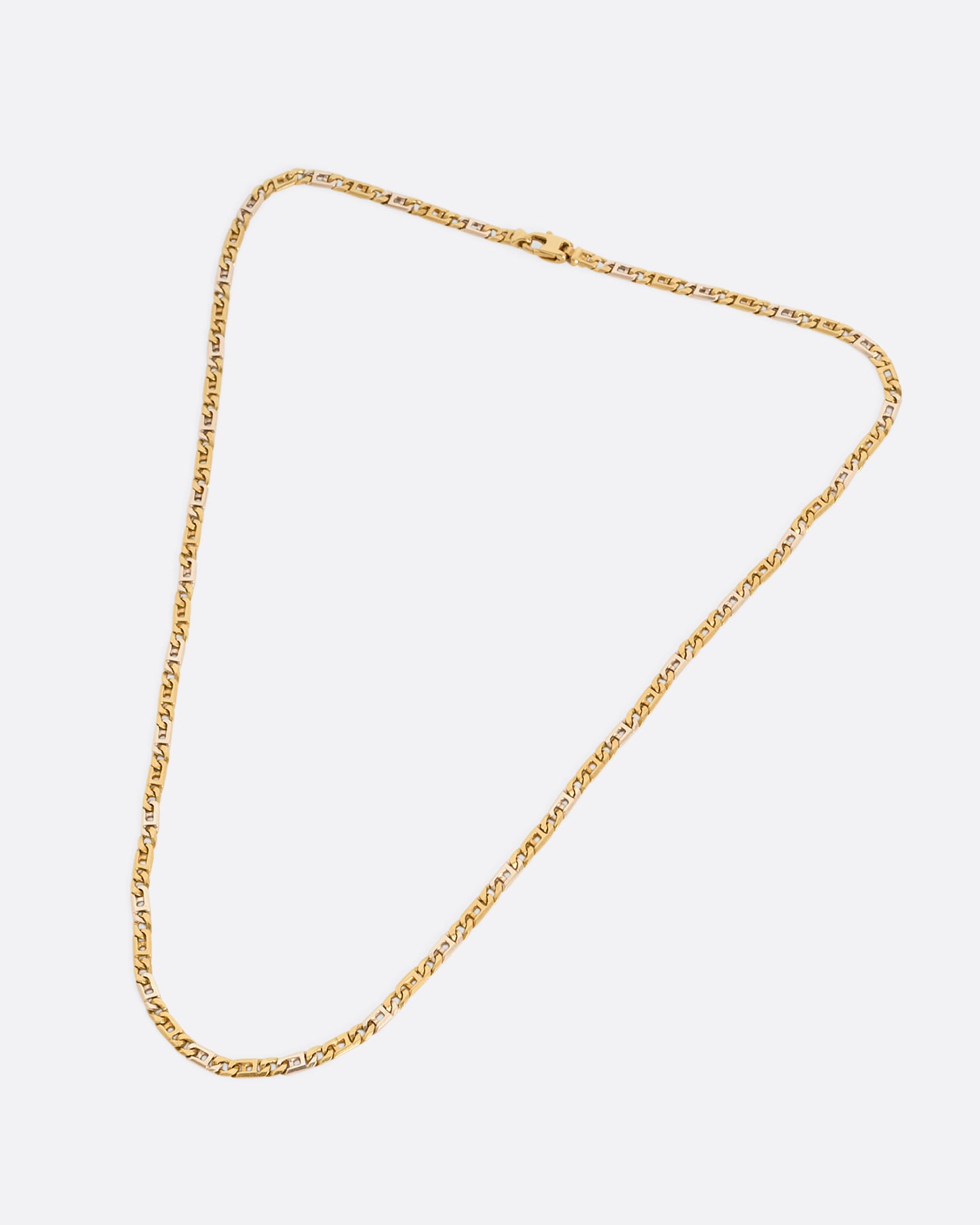 A white and yellow gold geometric flat chain necklace. Shown laying flat.