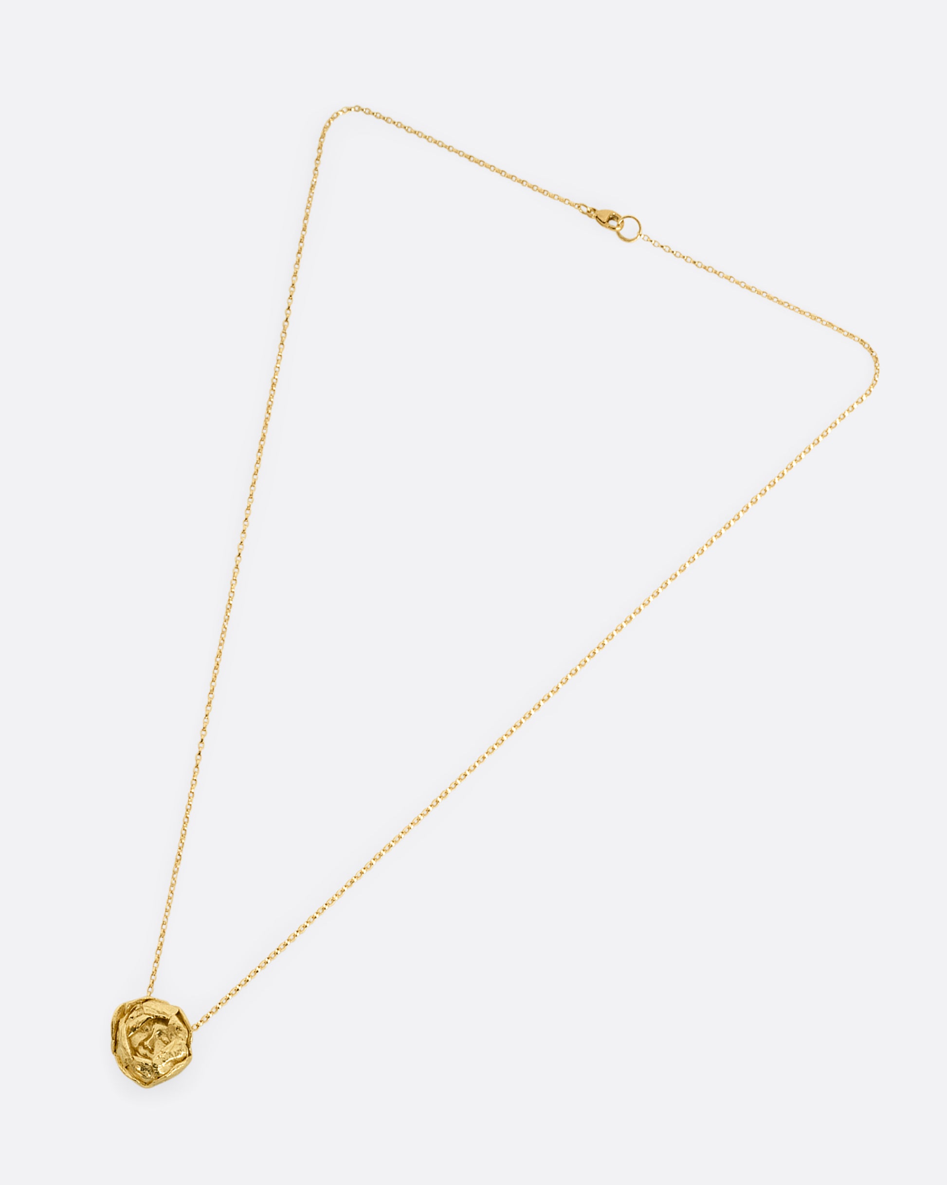 A yellow gold flower pendant with a sleeping face at its center on a cable chain. Shown from the front laying flat.