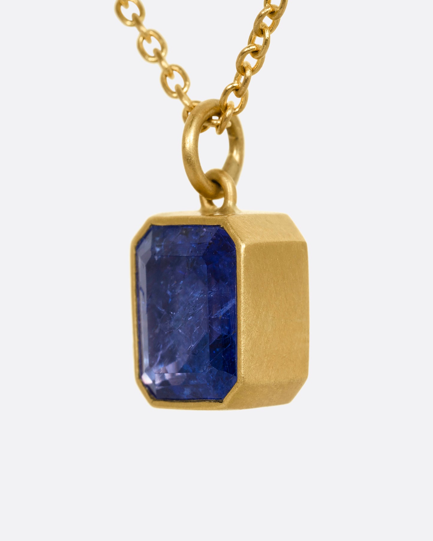 yellow gold necklace with an emerald cut tanzanite shown from the side