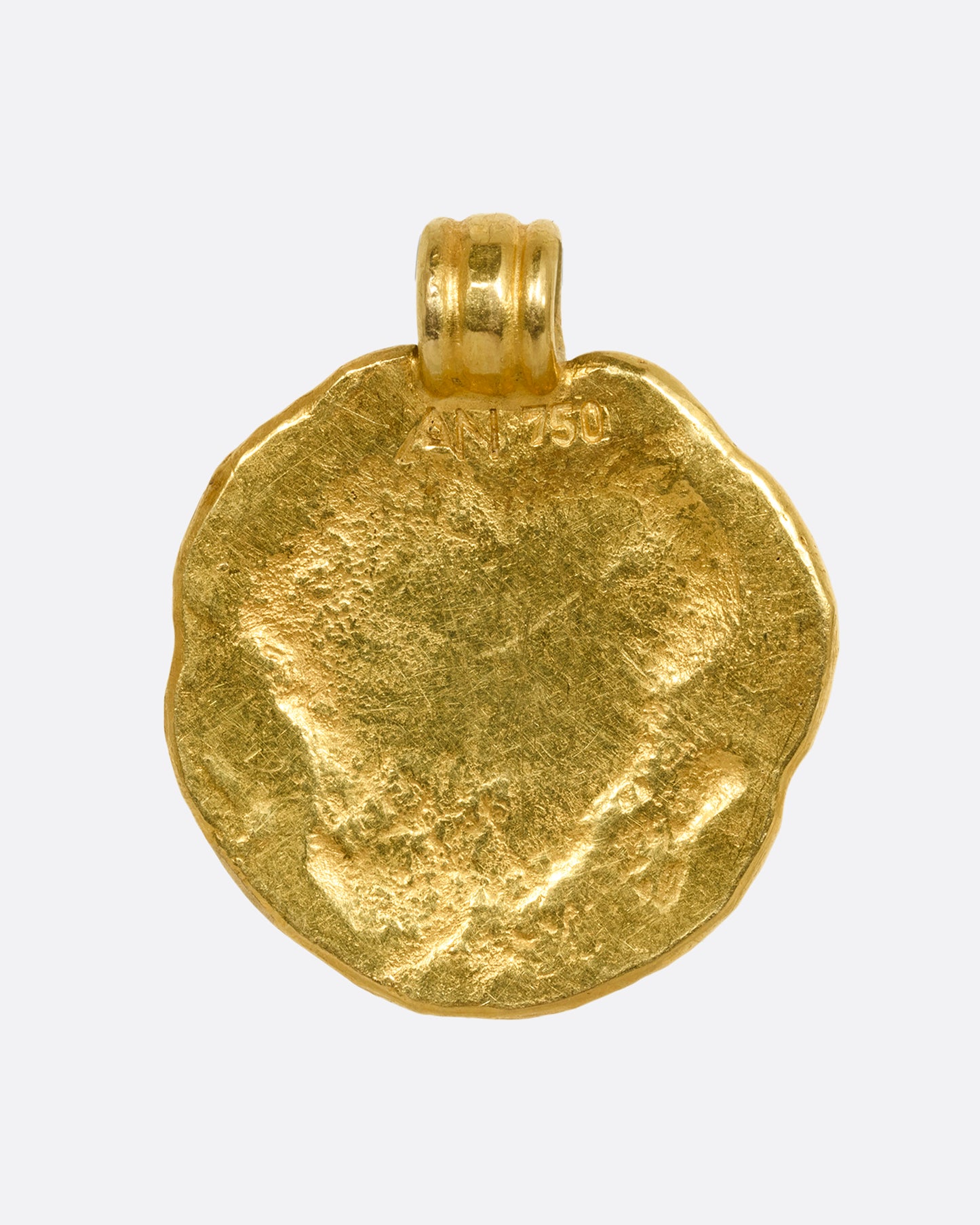 A high carat yellow gold organic circle pendant with the letter m on the face. Shown from the back.