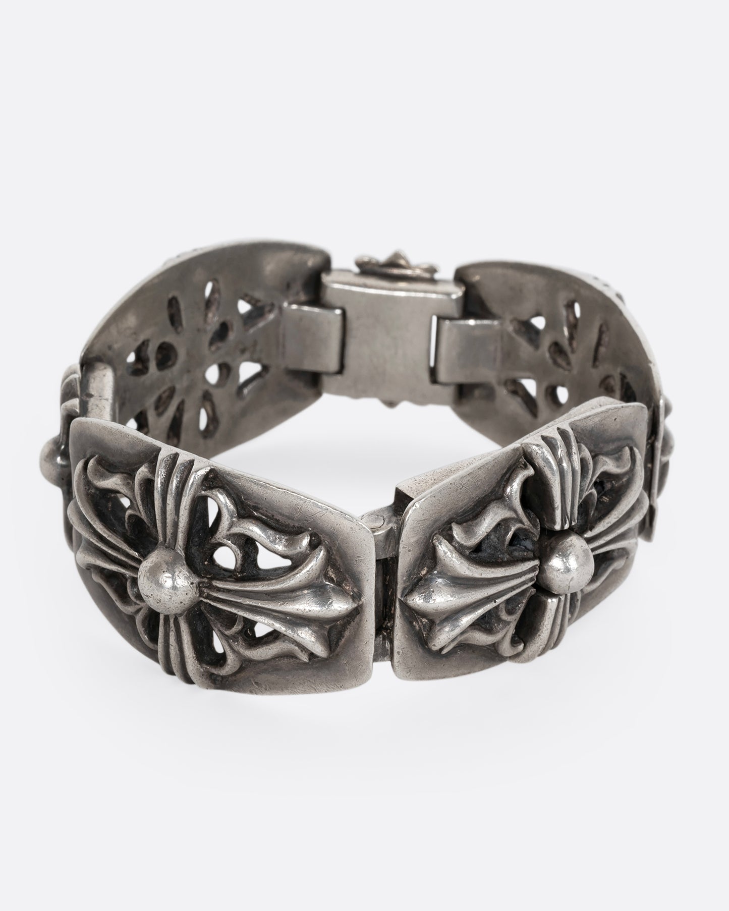 A sterling silver chunky bracelet from the brand Chrome Hearts with flower motifs on each link. Shown from the side.