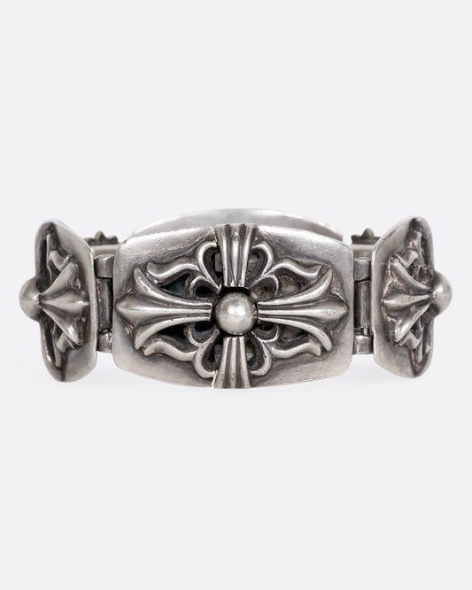 A sterling silver chunky bracelet from the brand Chrome Hearts with flower motifs on each link. Shown from the front.