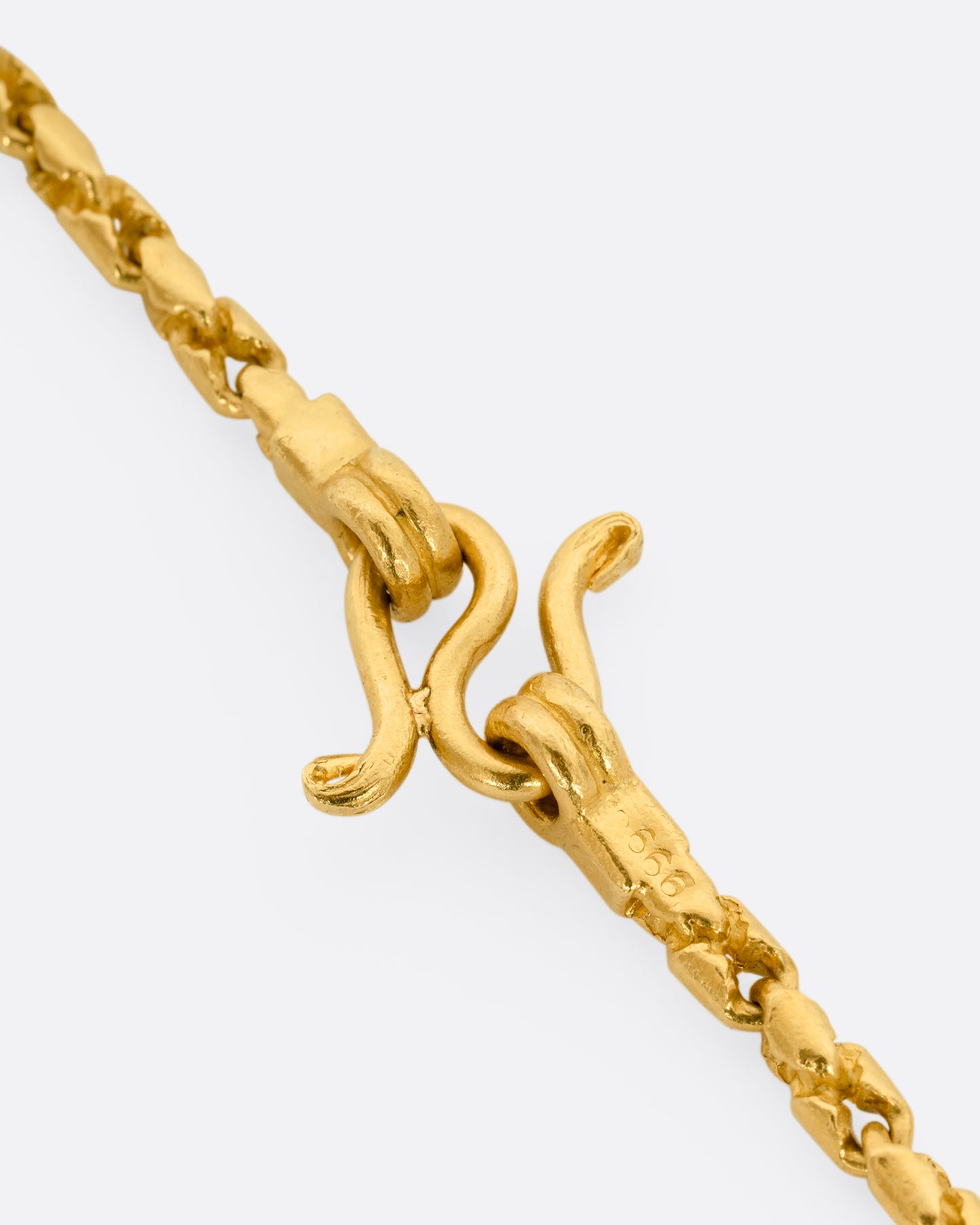 A high karat yellow gold Thai bhat chain. Shown hanging from the front. Shown close up on the clasp.