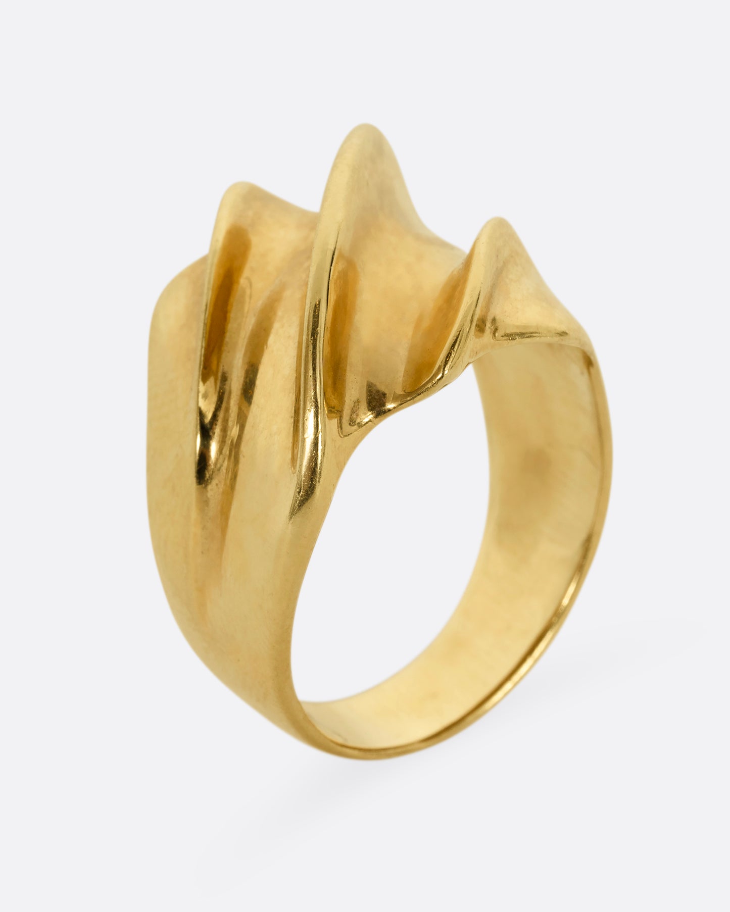 A chunky yellow gold wave ring. Shown from the side, standing up.