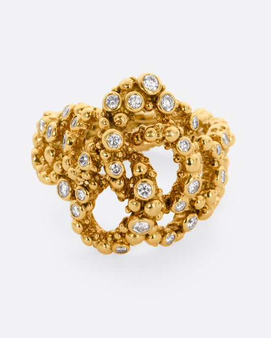 A yellow gold knotted ring with granule texture and diamonds throughout. Shown from the front.