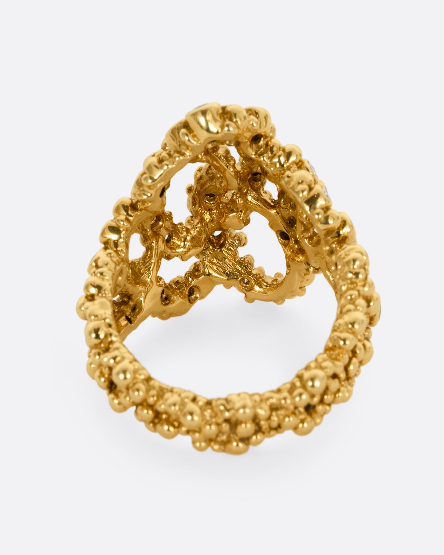 A yellow gold knotted ring with granule texture and diamonds throughout. Shown from the back.