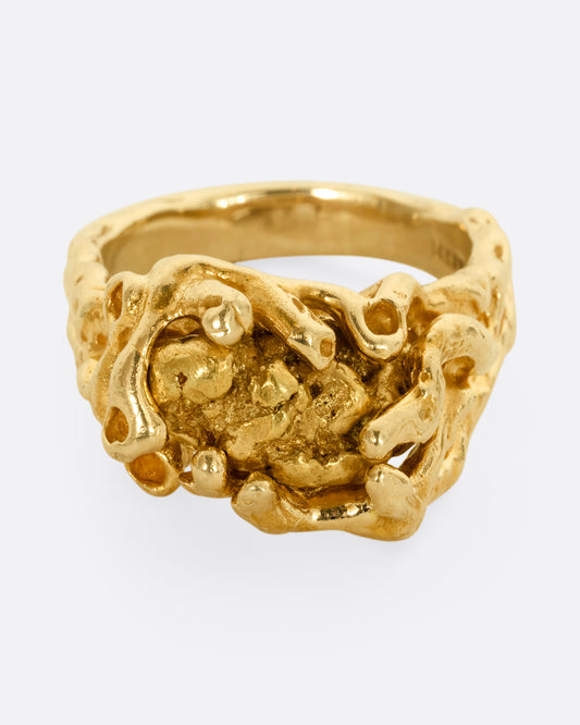 A yellow gold amorphous ring holding a high carat gold nugget. Shown from the front.