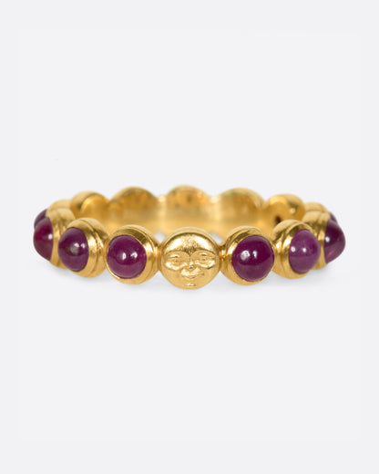 Yellow gold ruby band with moon face, front view of the band with the carved moon face between ruby cabochons