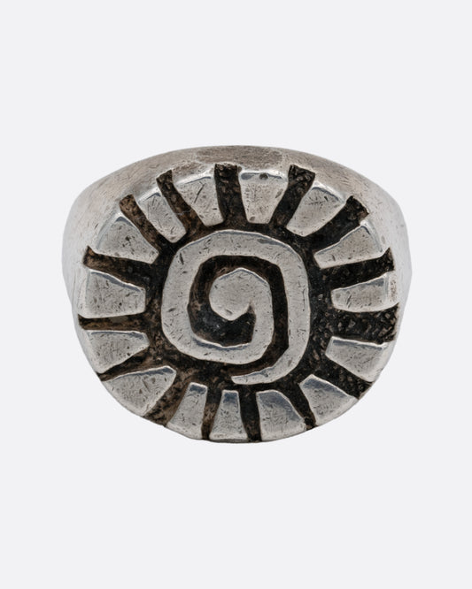 A silver ring with a graphic spiral sun, shown from the front.