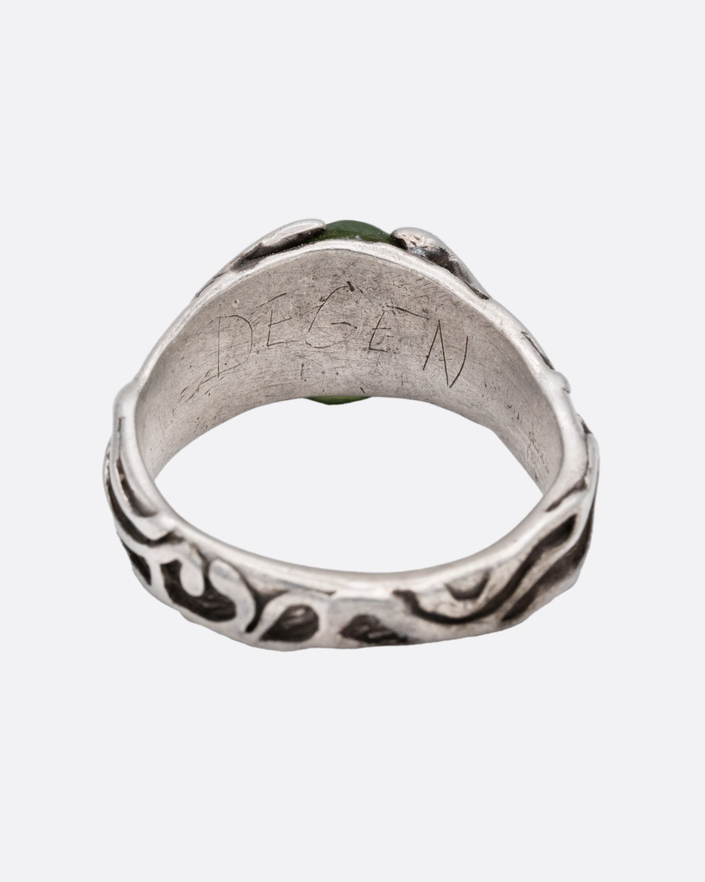 A silver ring with an oval jade at the center, shown from the back.