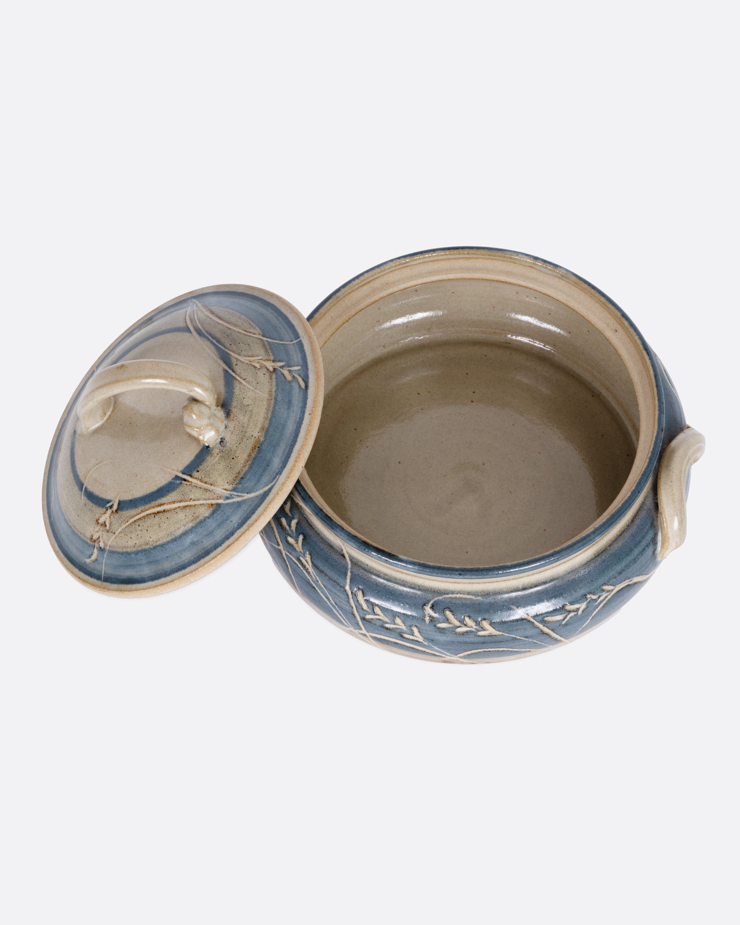 A blue and gray casserole dish with a domed lid and handles. Shown from the top with the lid leaning on its side.