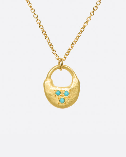 A hand-formed padlock pendant with three turquoise dots.