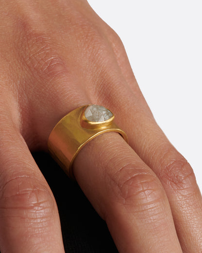 A wide, matte yellow gold hammered band with a rose cut gray diamond, shown on a hand.