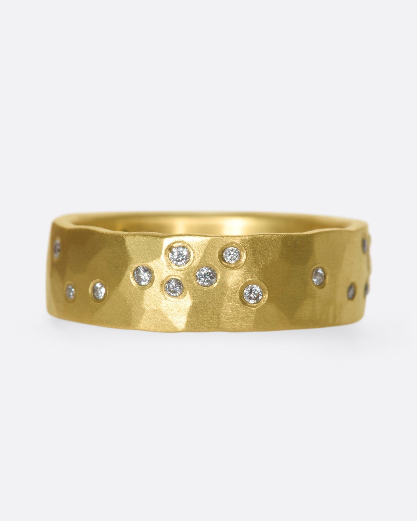 A constellation of thirty sparkling white diamonds set on a wide, hammered, matte gold band.