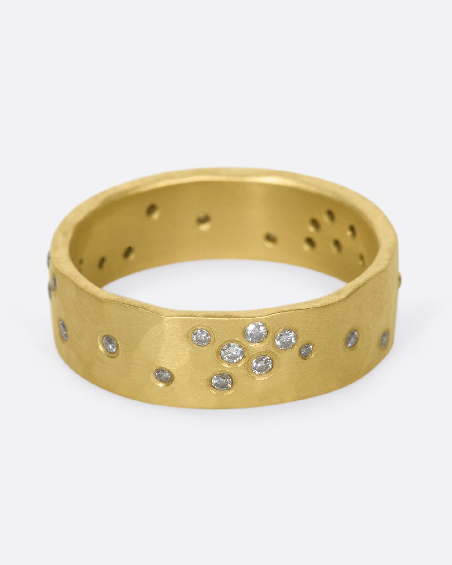 A constellation of thirty sparkling white diamonds set on a wide, hammered, matte gold band.