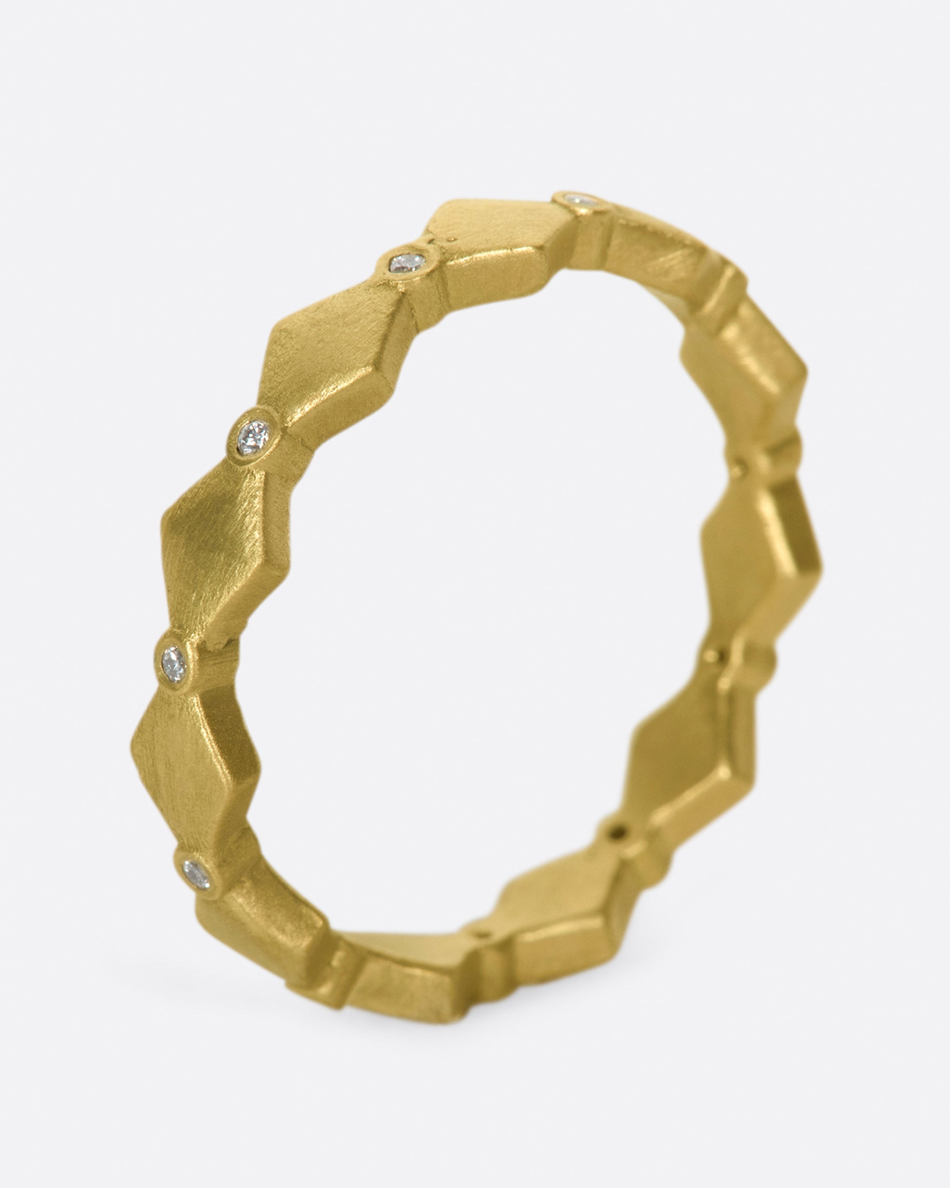 A geometric band with alternating round diamonds and matte gold shapes.