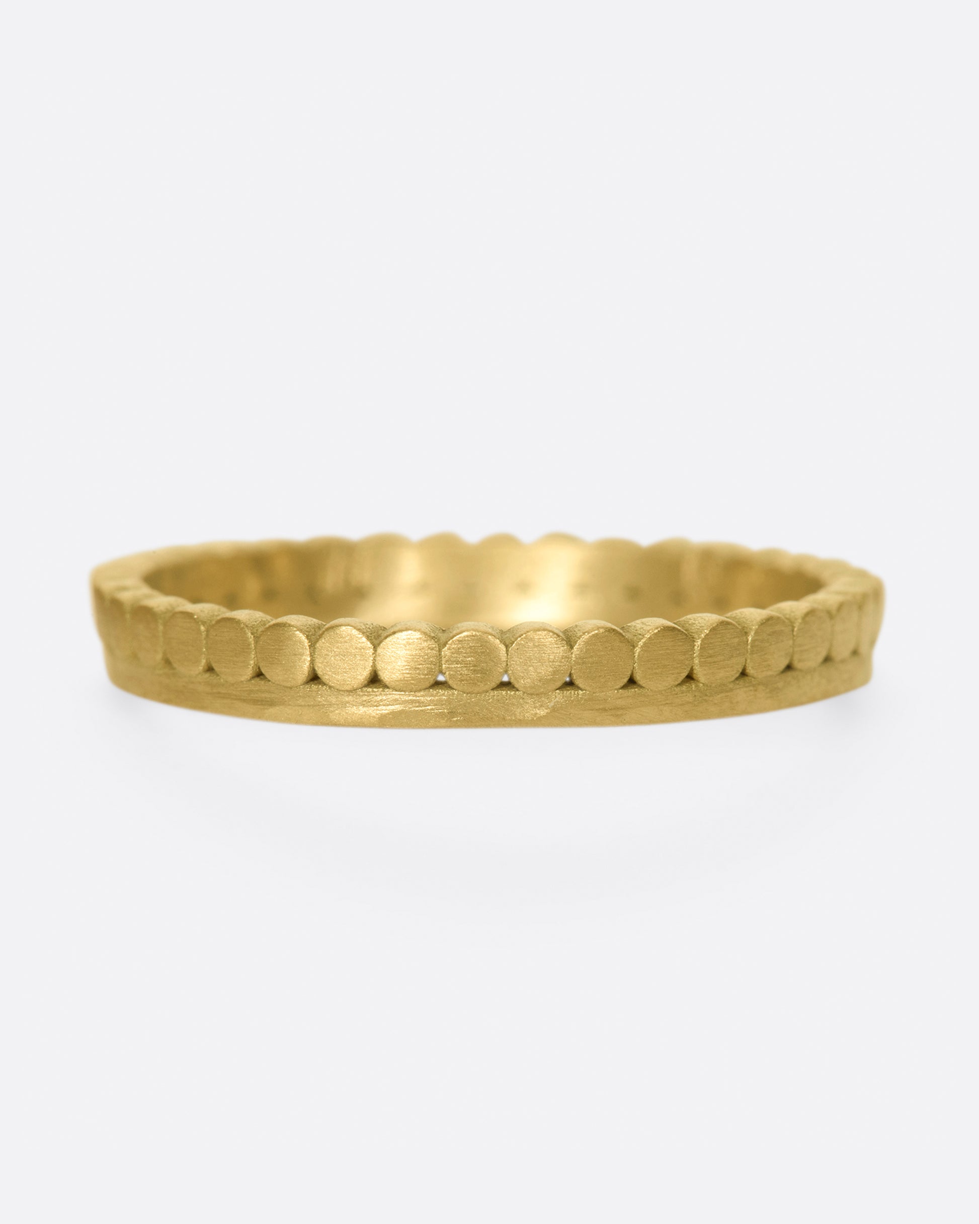 A matte gold band with dots encircling one side of the ring.