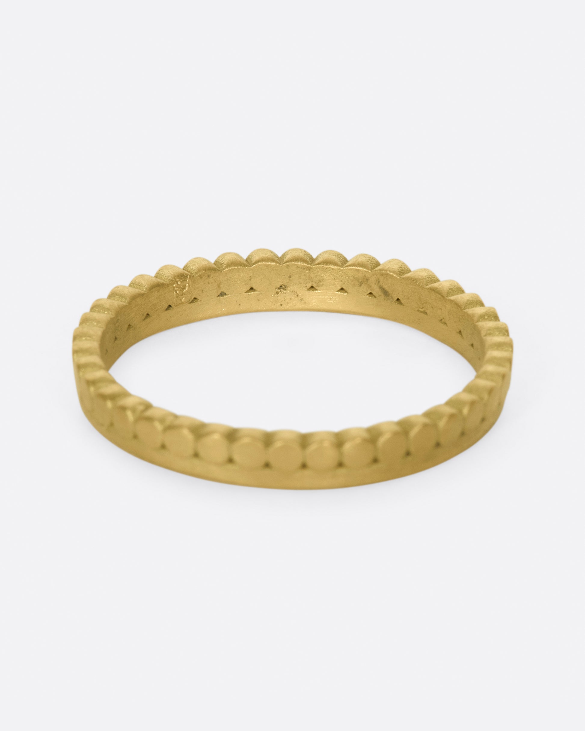 A matte gold band with dots encircling one side of the ring.