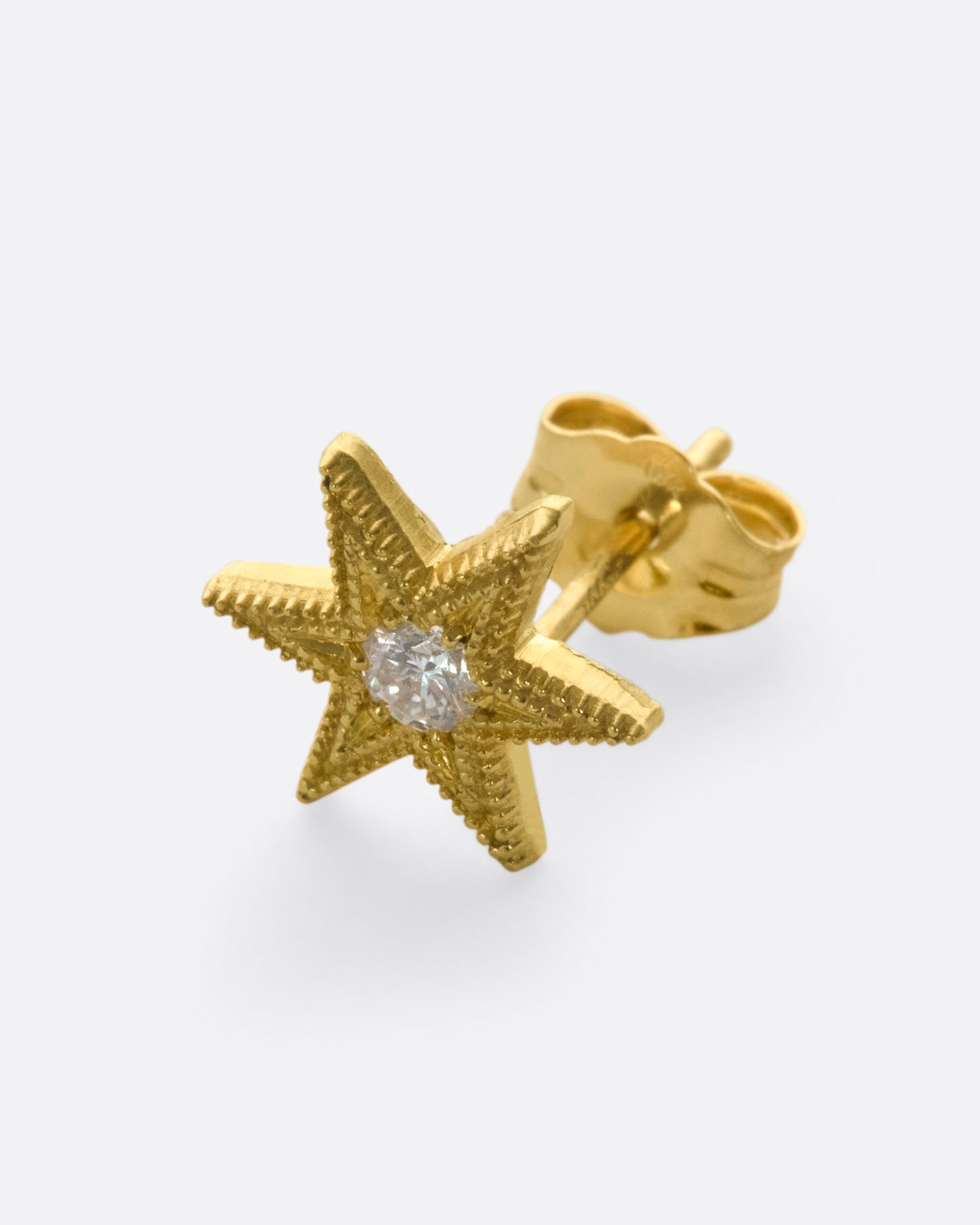 Yellow gold star stud earring with six points and millgrain details.