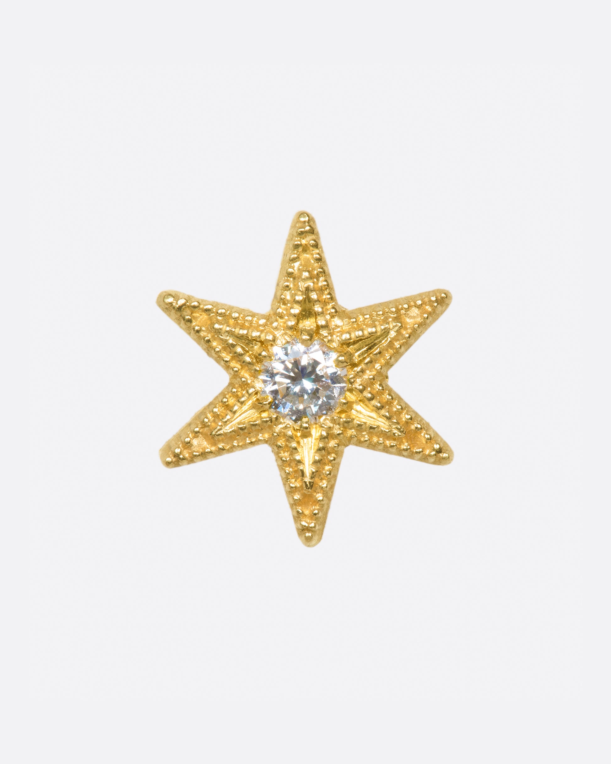 A six point star with millgrain texture and a bright white diamond center.
