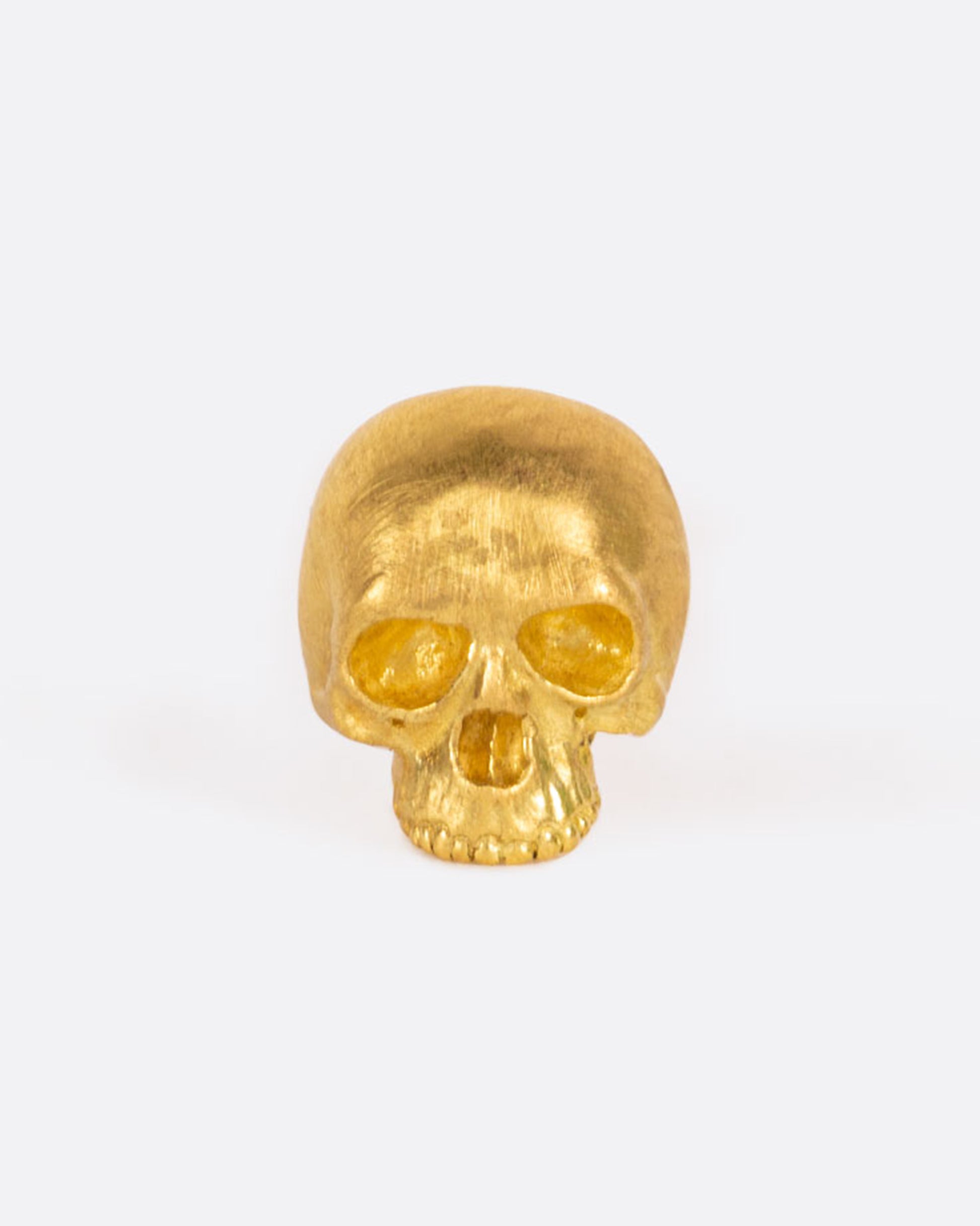 A tiny solid yellow gold skull stud, carved to anatomical perfection by Anthony Lent.
