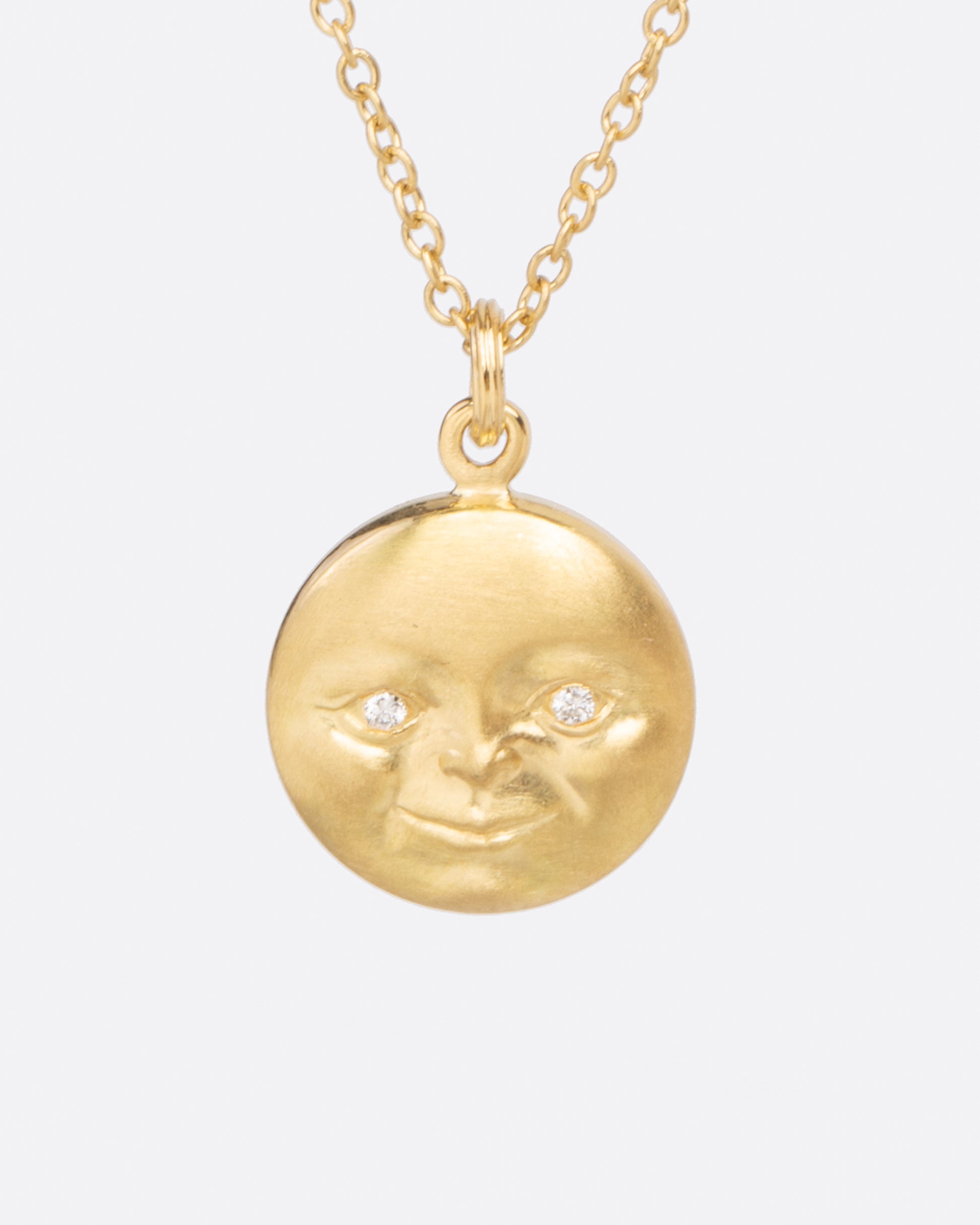 A highly detailed moonface with little diamonds eyes hangs from a sturdy chain.