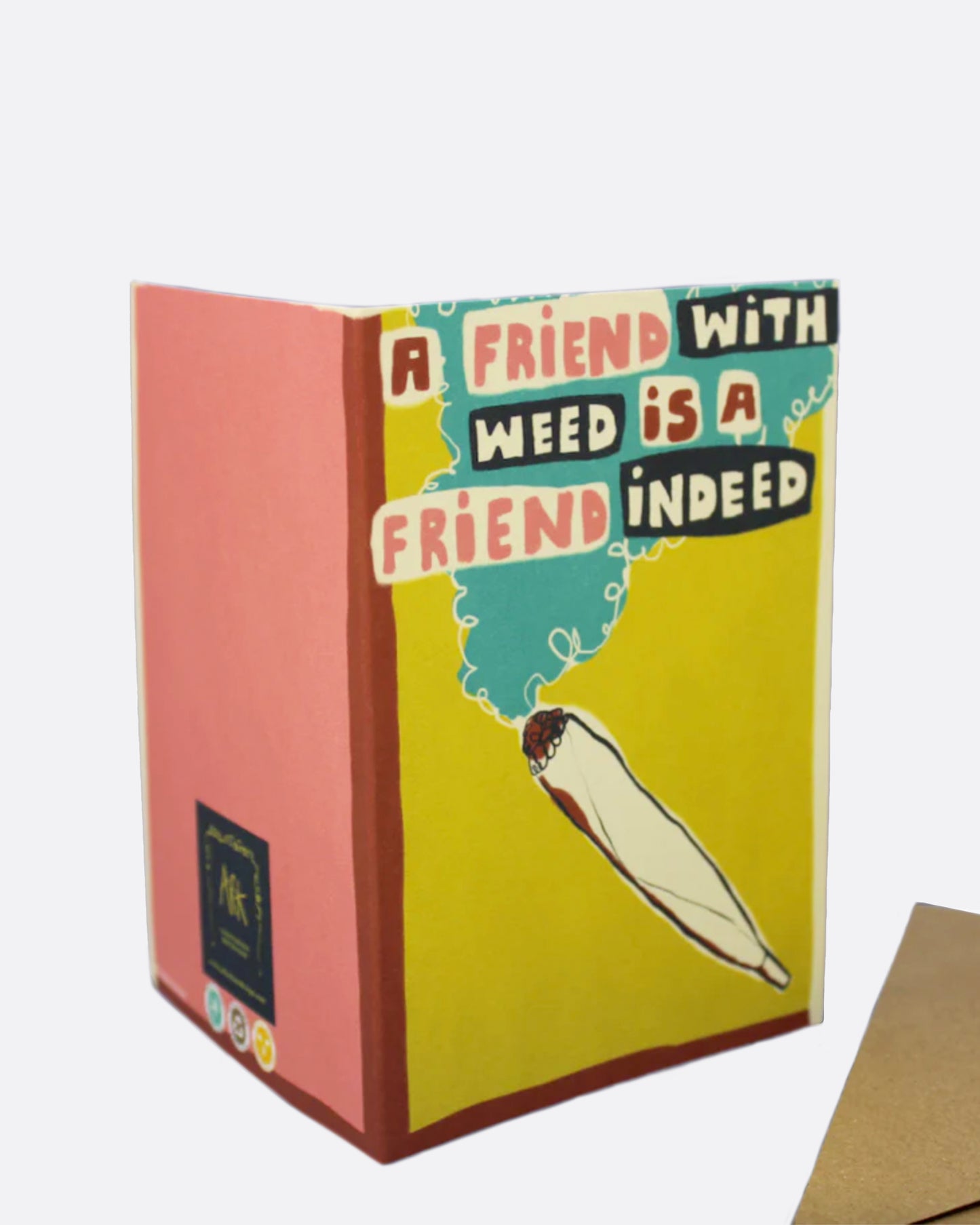 A yellow greeting card with a joint on the front and the words 'A friend with weed is a friend indeed,' and a black white interior. Shown with its kraft paper envelope.