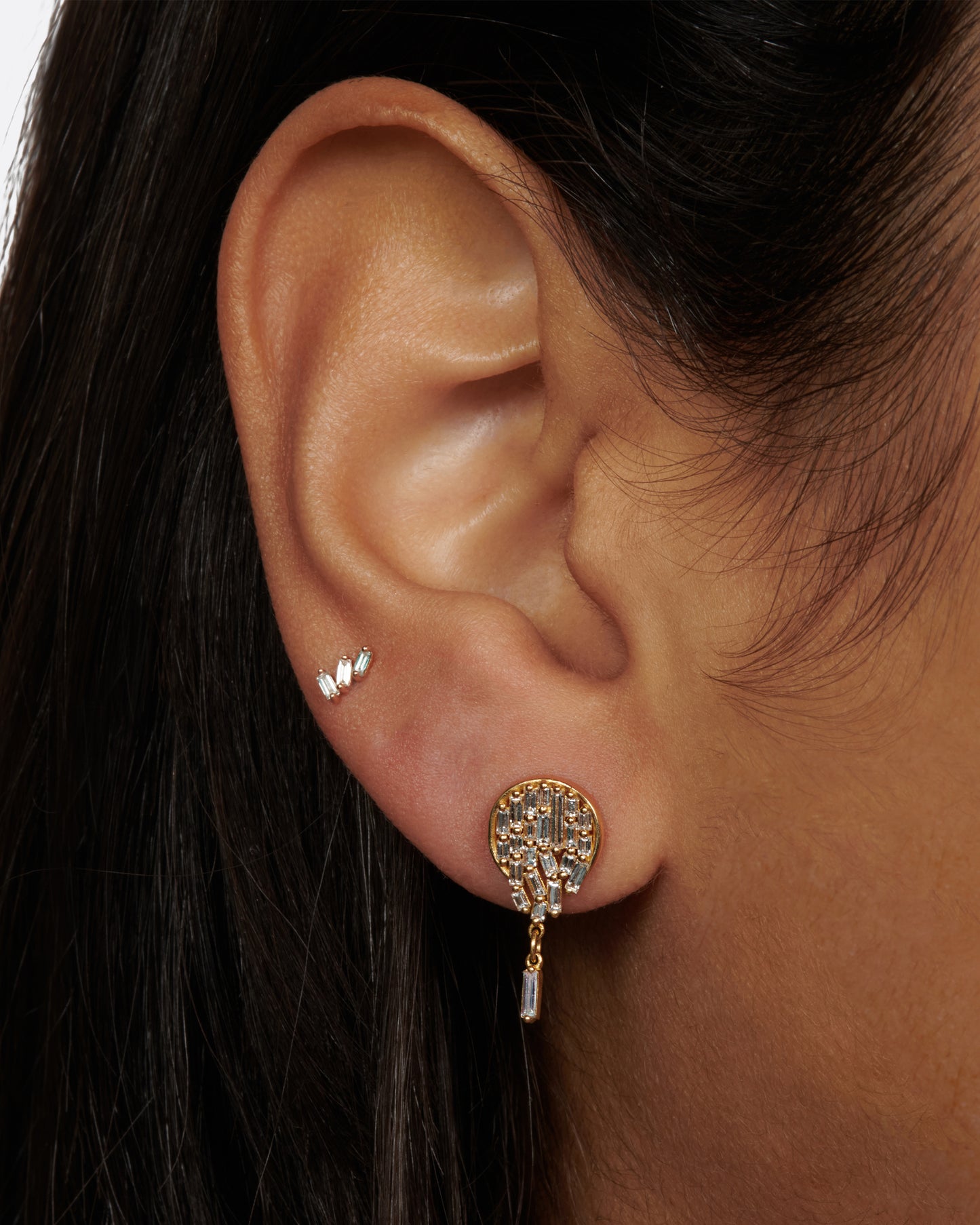 A pair of round stud earrings dripping with diamond baguettes.