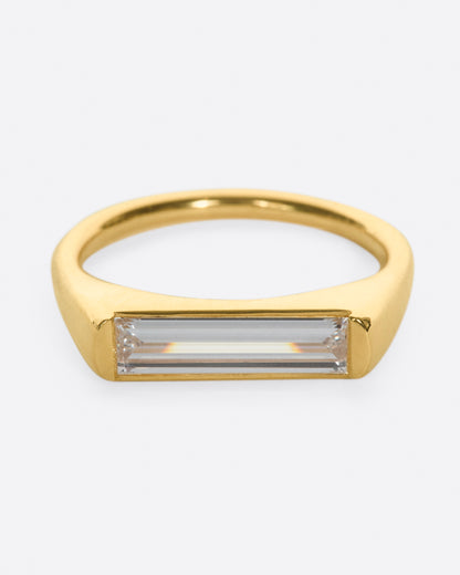 Yellow gold baguette diamond ring, front view of the baguette diamond with the band curving behind it