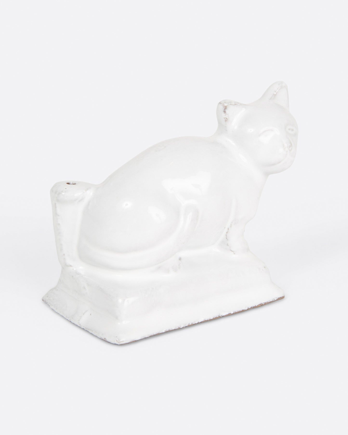 A glazed white ceramic cat-shaped incense holder, shown from the side.