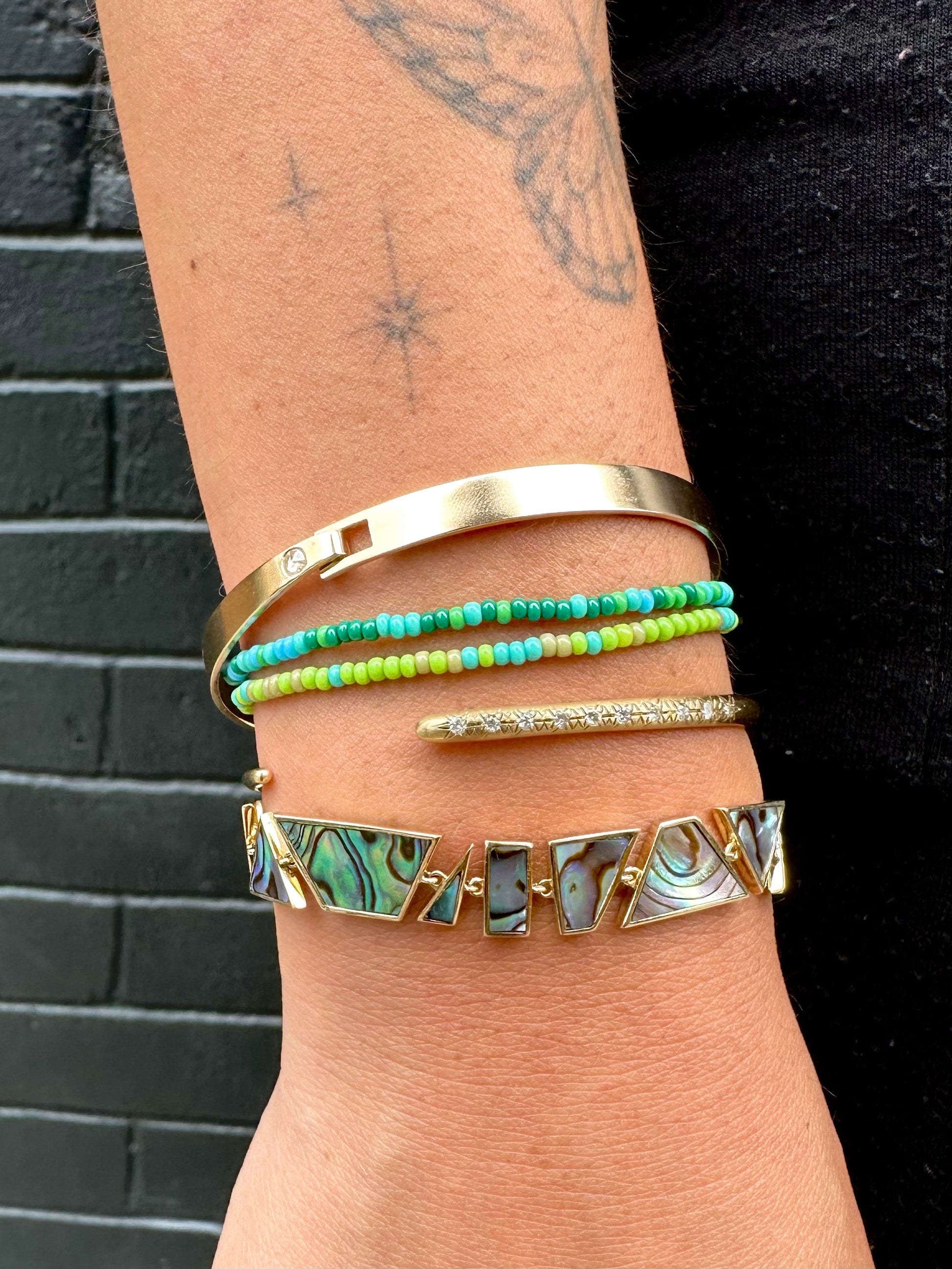 A wrist shown styled with five different bracelets. 