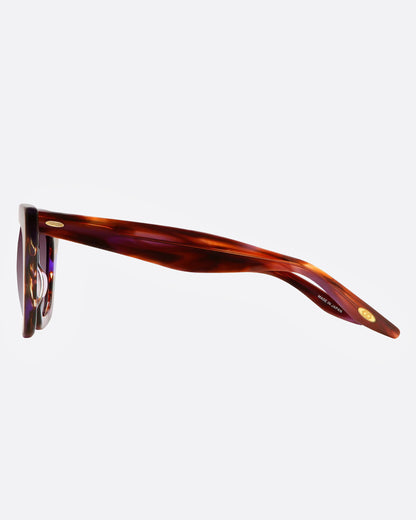 A pair of sunglasses with tortoiseshell frames with flecks of purple and gradient lenses, shown from the side.