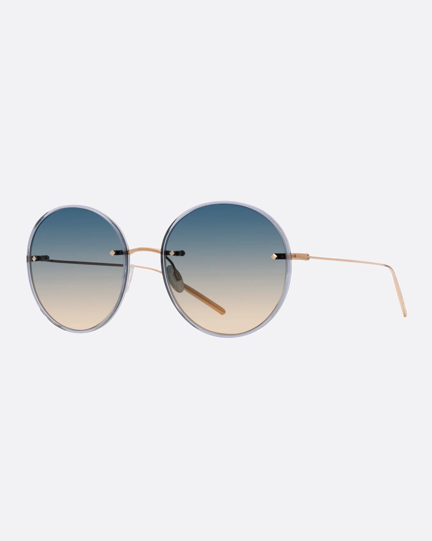 A pair of gold titanium sunglasses with large round blue to yellow ombré lenses with narrow light blue acetate frames. Shown from the side.