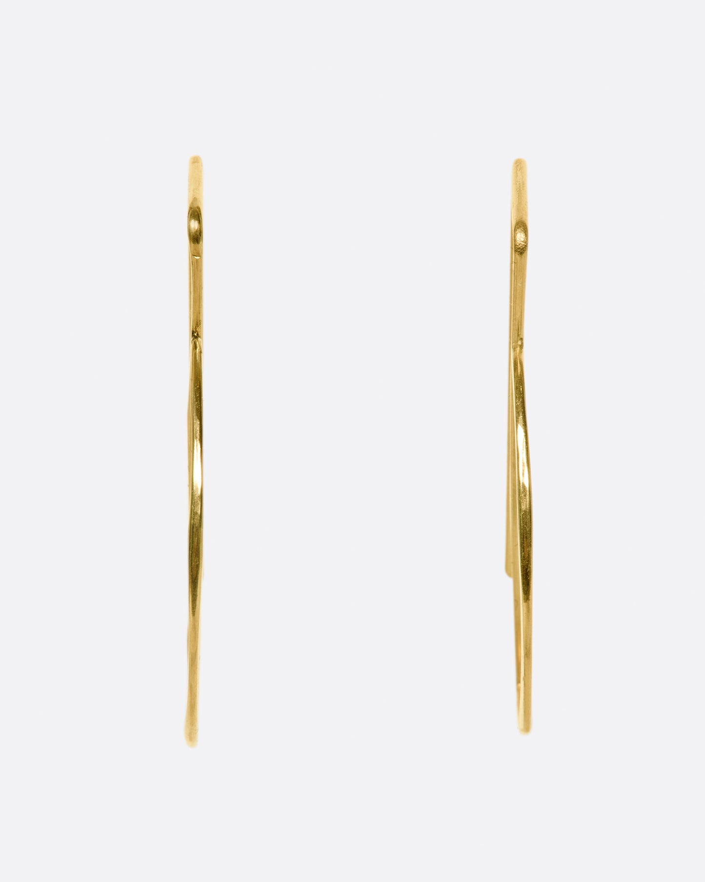 These hammered gold earrings thread through the ear so that the straight bar sits comfortably behind your lobe and the curve shows in front.