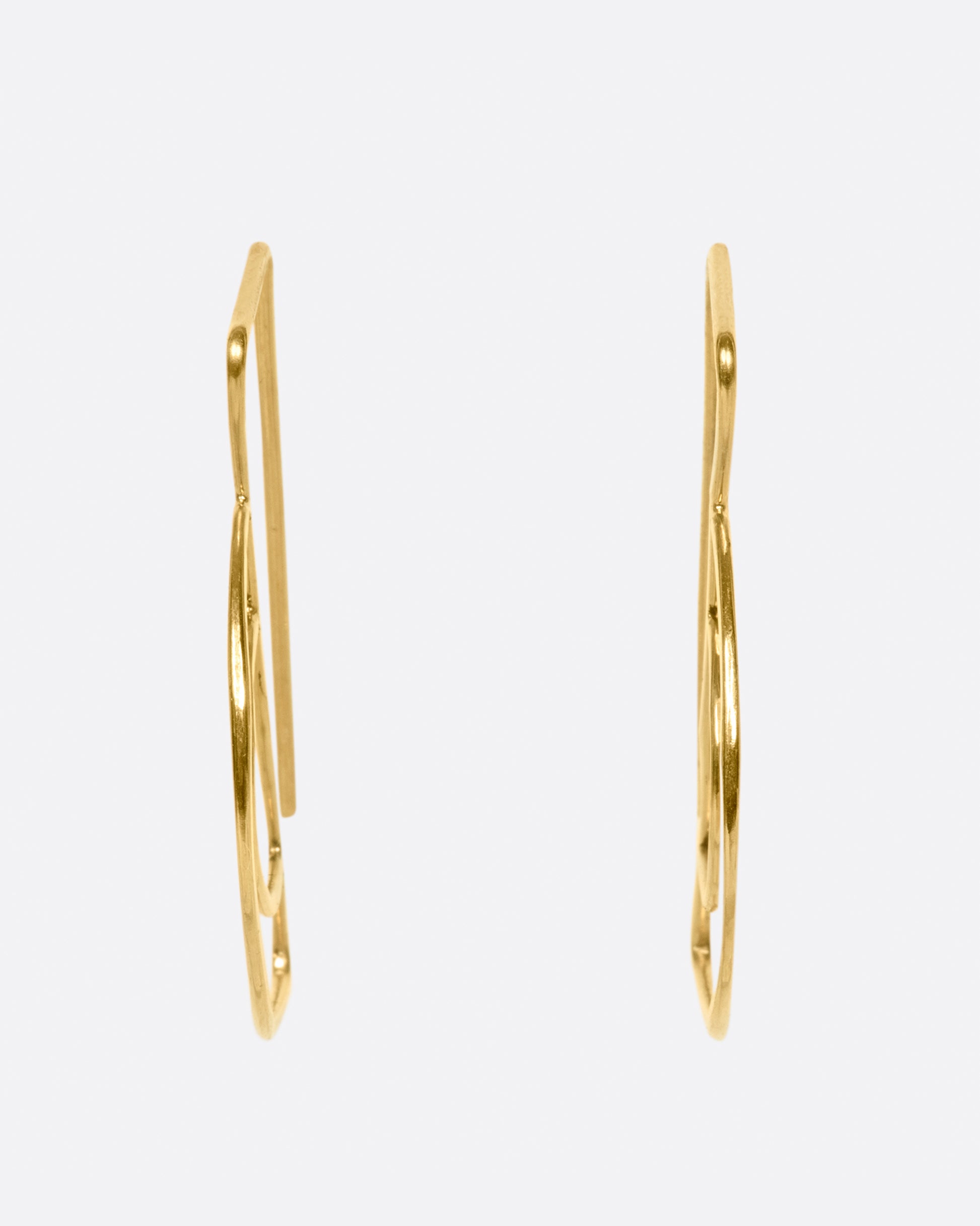 These double semi-circle earrings face forward and the long straight wires hang behind the earlobe; framing the face.