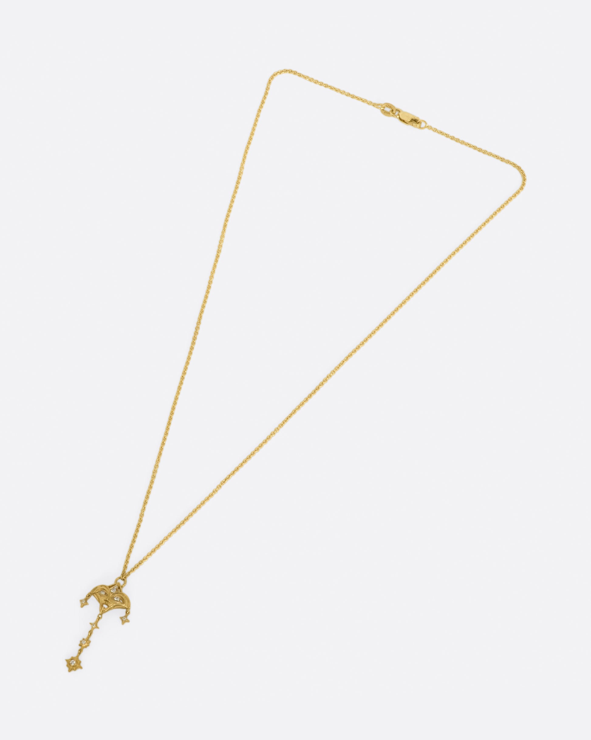 A yellow gold necklace with a mask pendant with diamond eyes and various star dangles.