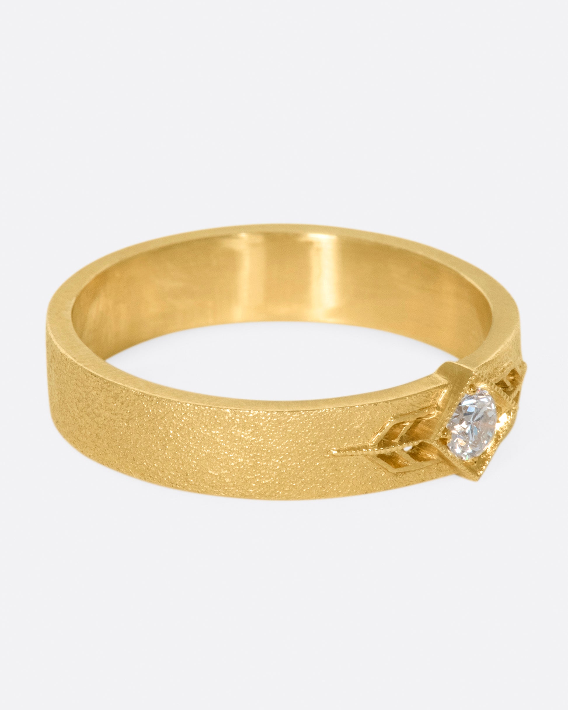 This 14k gold band has a stipple textured finish and an extremely sparkly, high-quality diamond popping in the center
