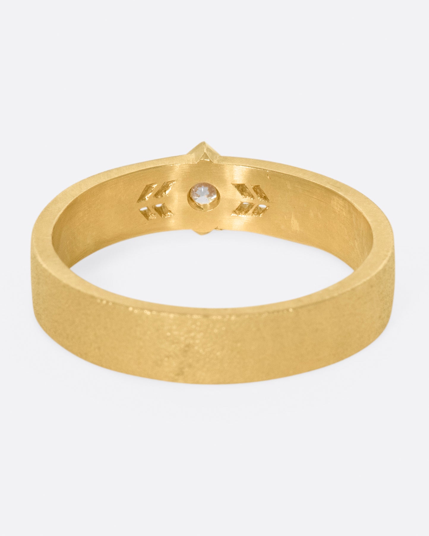 This 14k gold band has a stipple textured finish and an extremely sparkly, high-quality diamond popping in the center