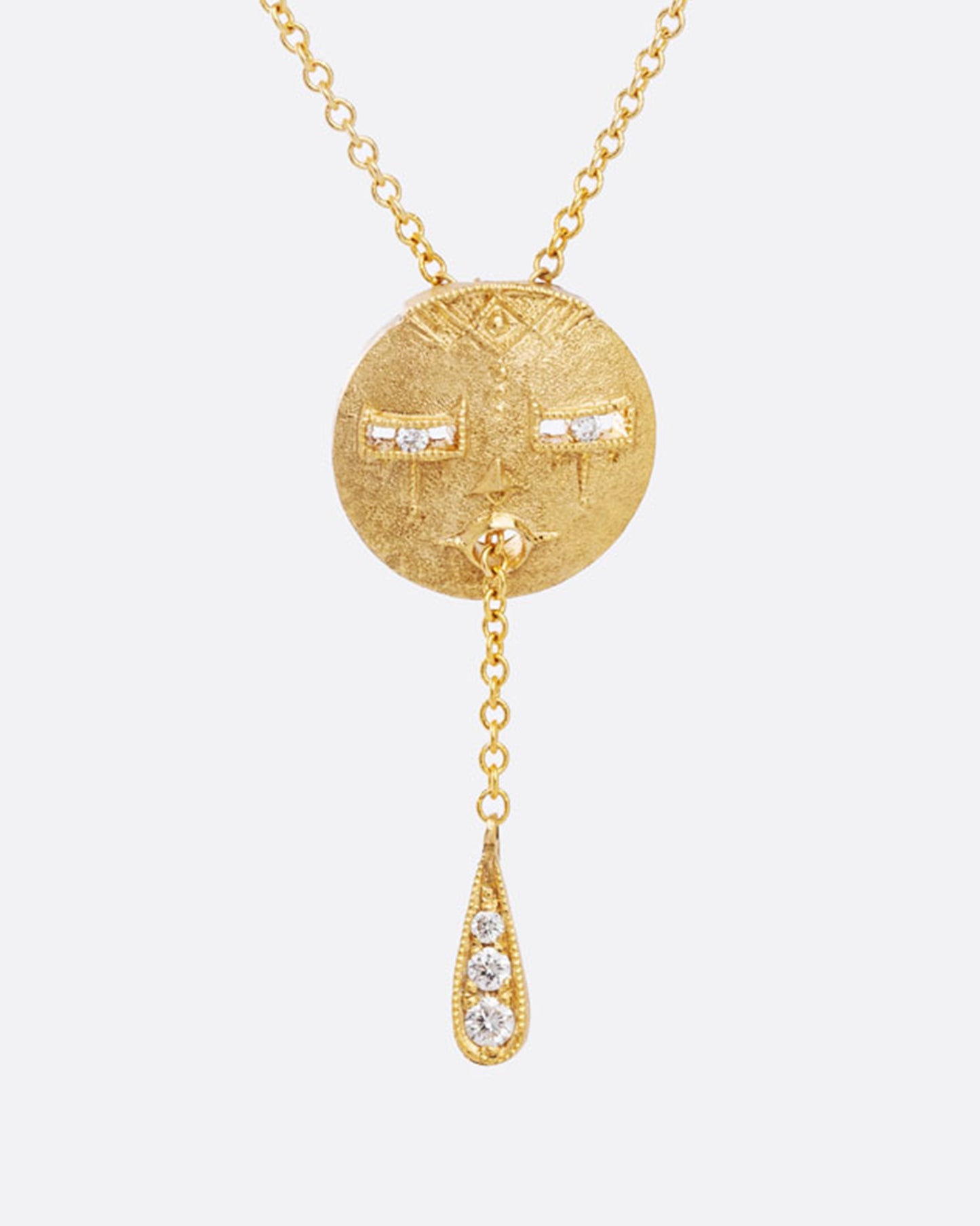 Yellow gold lariat necklace with carved face diamond eyes and a drop chain with a triplet of diamonds.