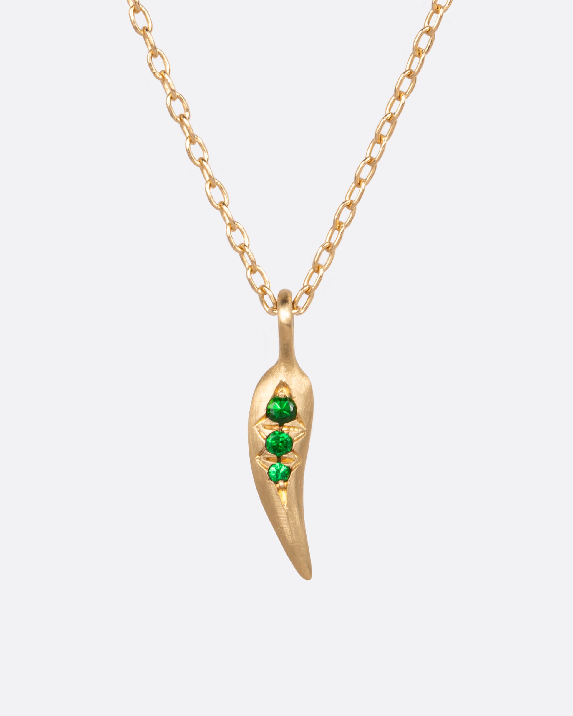 A small chili pepper shaped pendant with three vibrant green tsavorite garnets.